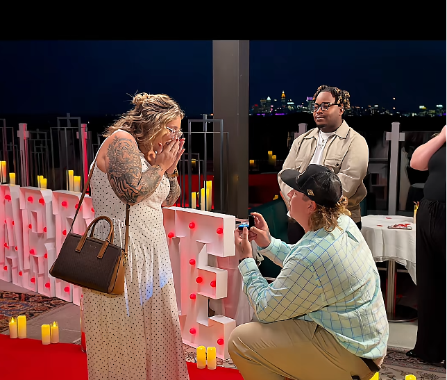 Pumpkin Efird covers her mouth in disbelief as Darrin Kitchens kneels before her with an engagement ring during a romantic rooftop proposal. Her sister Alana Thompson’s boyfriend, Dralin Carswell, watches from nearby as the special moment unfolds. | Source: TikTok/Mama P