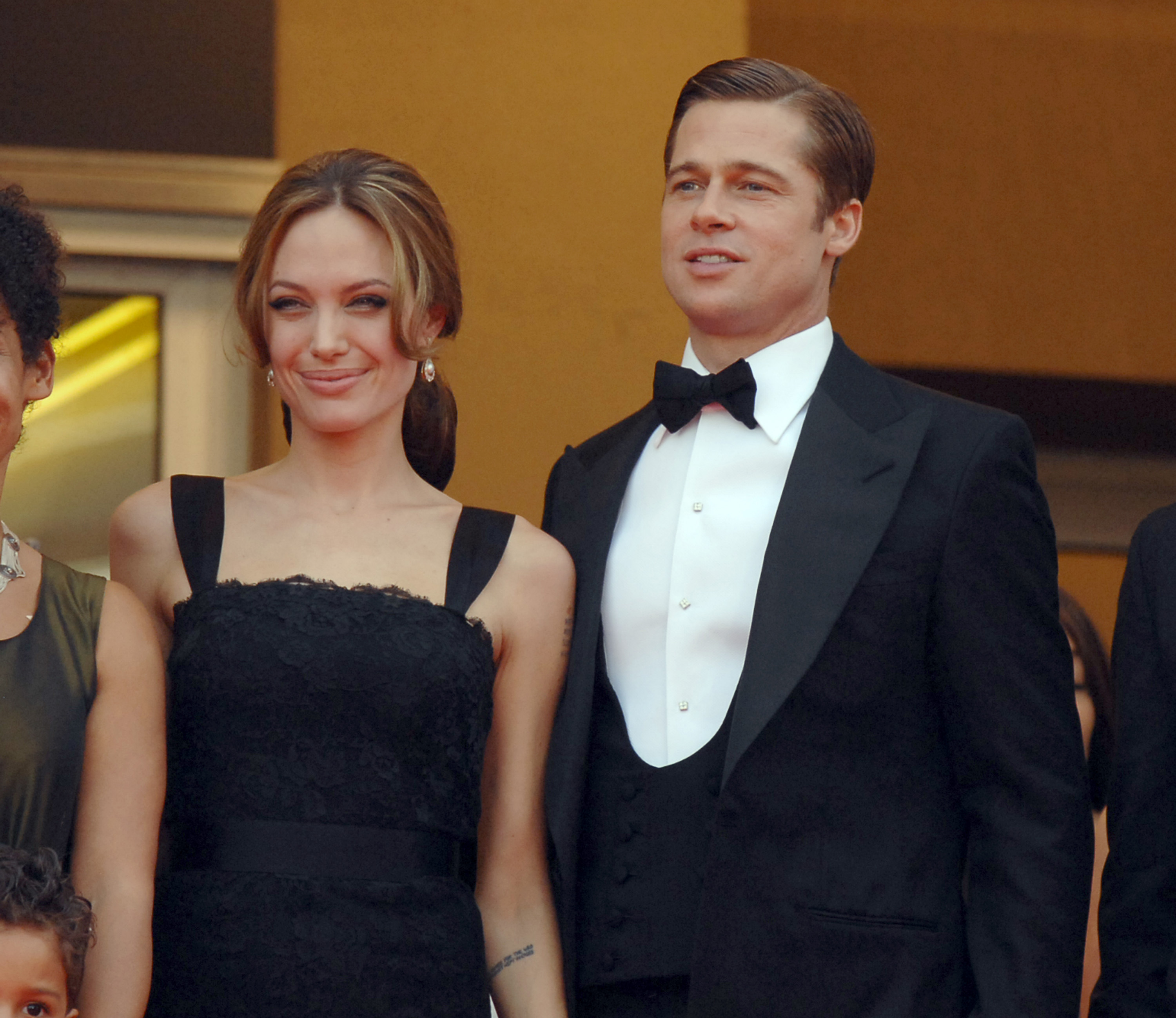 Angelina Jolie smiles beside Brad Pitt as the couple appear in coordinated black formalwear during the Cannes Film Festival premiere of "A Mighty Heart" in France.