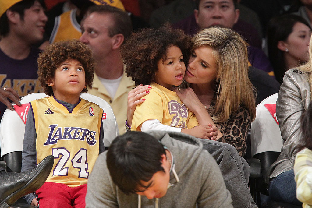 At a game between the New Orleans Hornets and the Los Angeles Lakers, Heidi Klum shared a courtside moment with her sons. Holding one on her lap while she whispered to him affectionately, the other looked up. Both boys wore Lakers jerseys, fully immersed in the game.