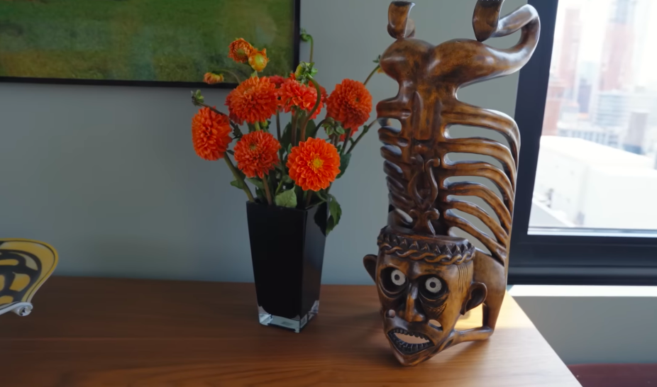 Not every artwork here is designed to disappear politely into the background. This striking carved figure captures Christopher's affection for pieces that are a little "creepy, interesting, whimsical." | Source: YouTube/Architectural Digest