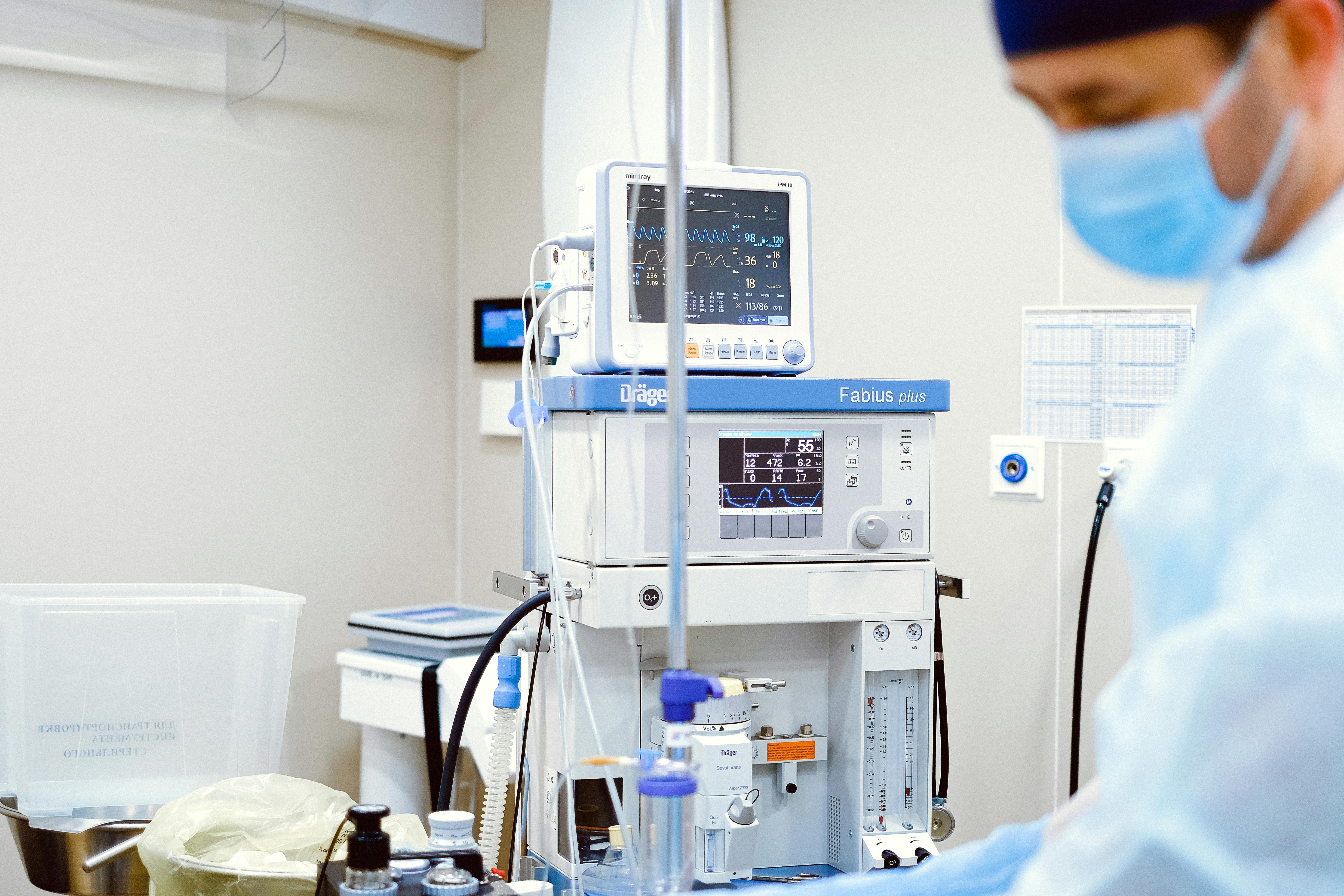 A doctor wearing a facemask stands by various medical monitoring devices. | Source: Pexels