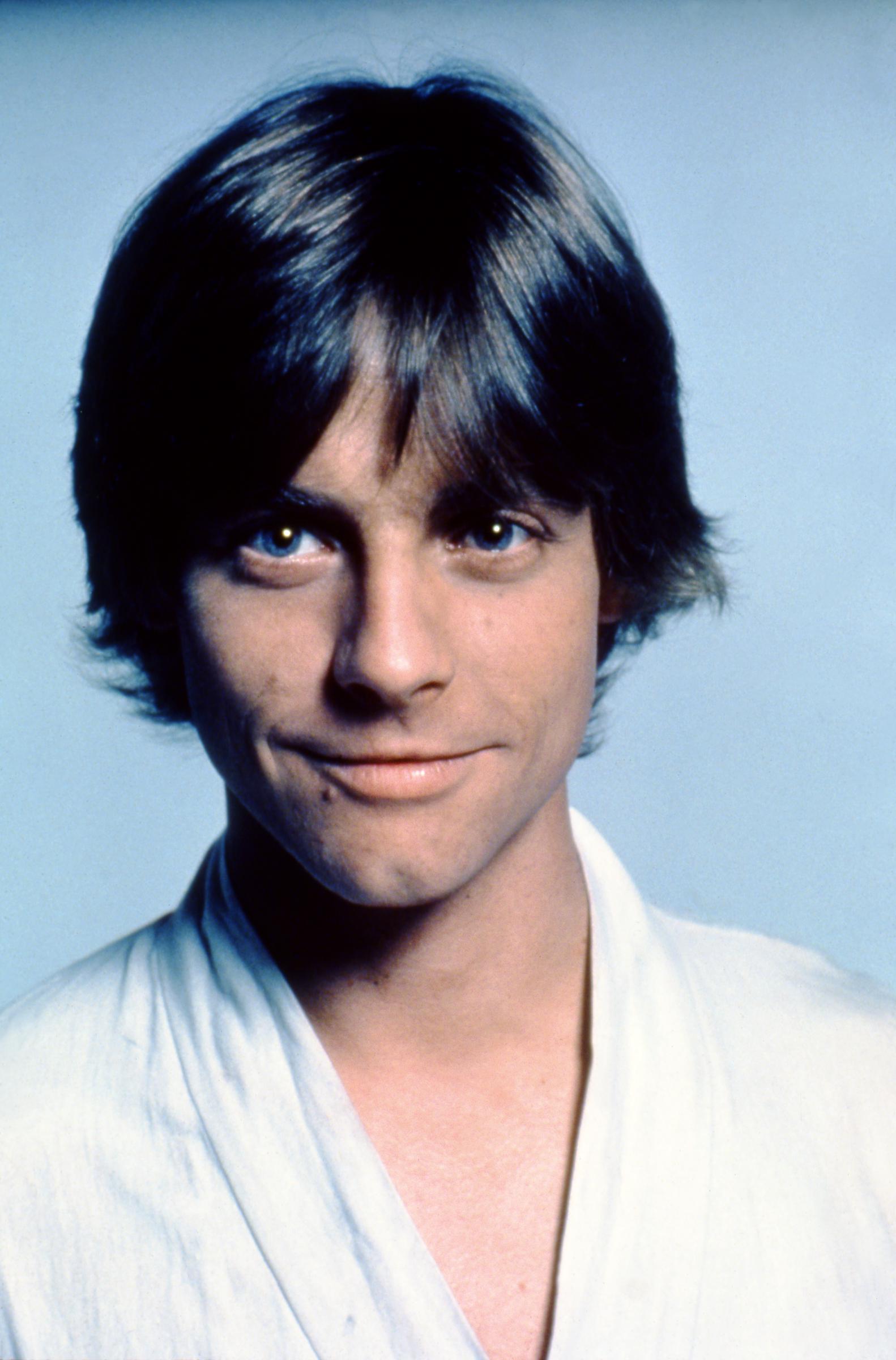 A close-up portrait of Mark Hamill as Luke Skywalker during production of "Star Wars: A New Hope" offered a detailed view of the actor before the film became a worldwide phenomenon. With his dark hair framing his face and Luke's white costume visible, Hamill was still months away from sudden fame. The portrait also documented his features before the 1977 crash that fractured two facial bones and required reconstruction.