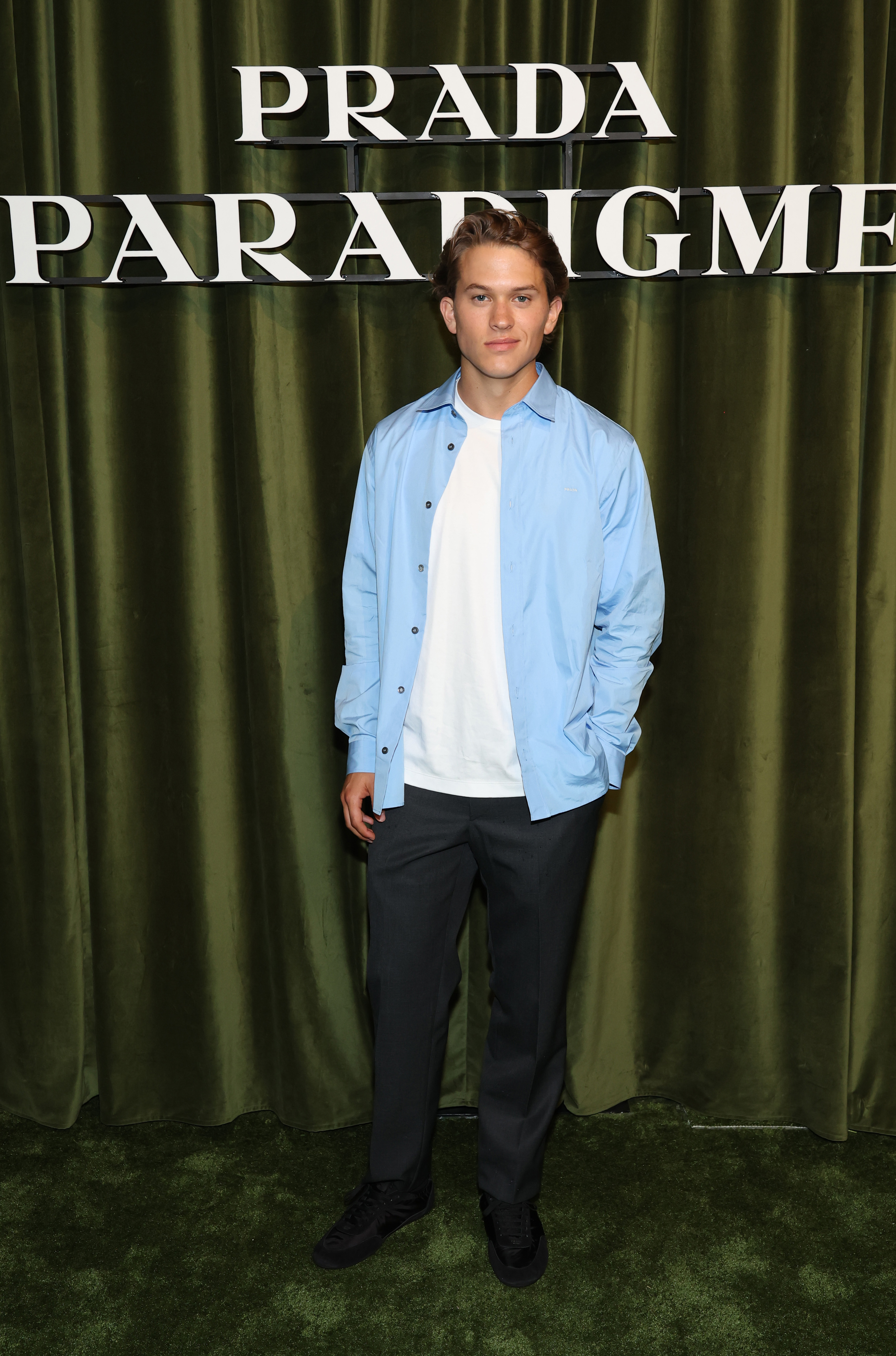 Deacon Reese Phillippe attends Prada's Paradigme Global Launch Party in New York City, posing solo in a pale blue shirt, white tee, dark pants, and black sneakers. | Source: Getty Images