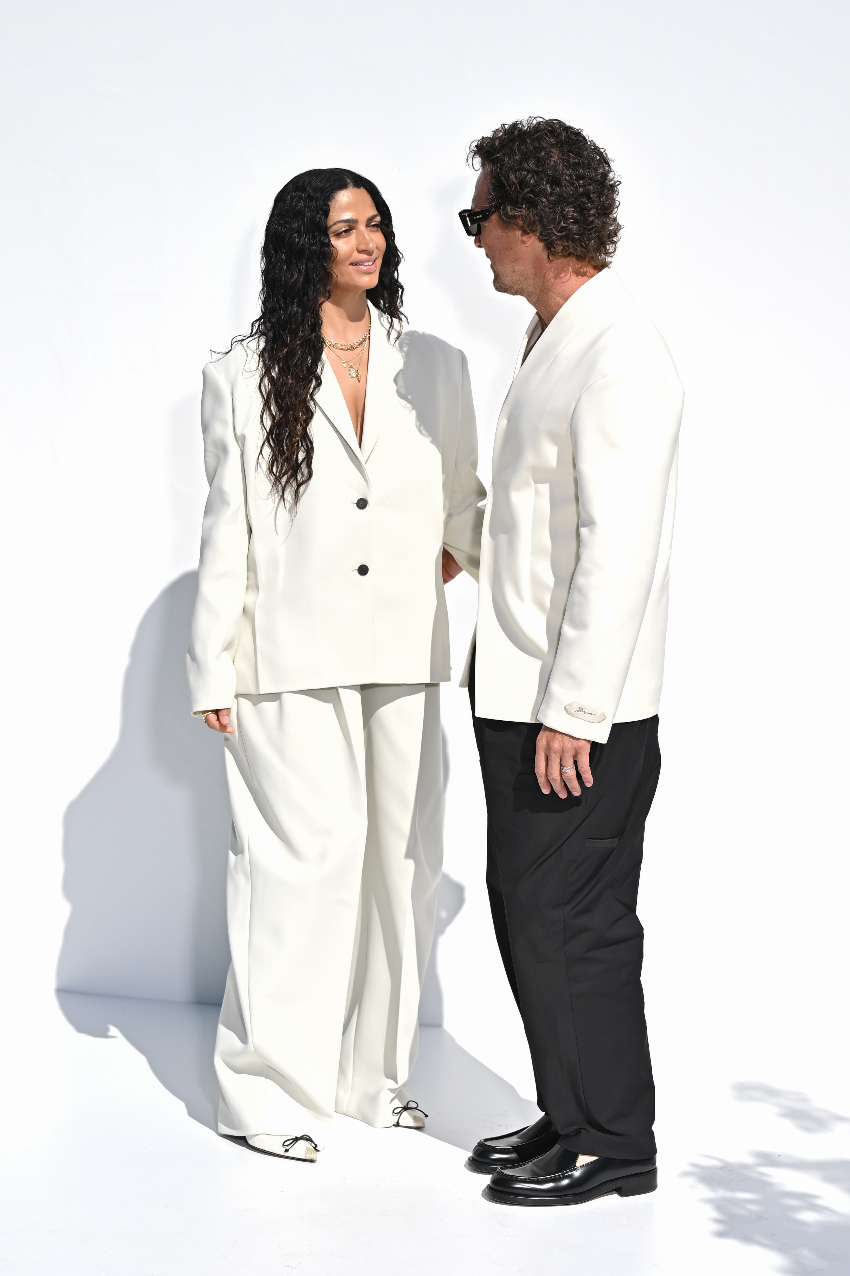 During a photocall set against a simple white background, McConaughey and Alves stand out effortlessly in their coordinated cream ensembles. The couple appears at ease and happy in each other’s company, their matching looks enhancing their natural chemistry.