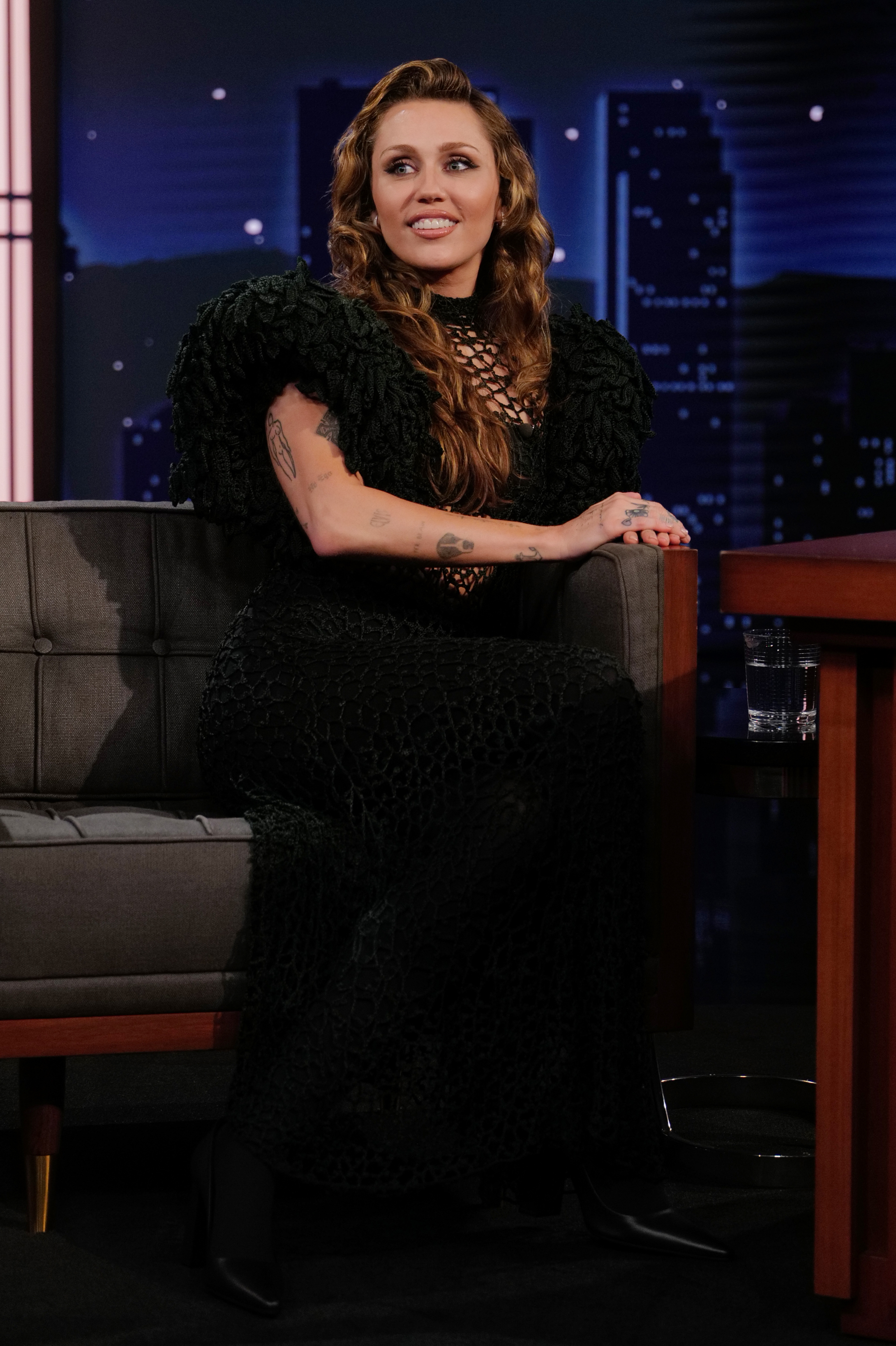 Miley Cyrus appeared on a talk show in a textured black gown, her long brunette hair styled in loose waves. In her conversation about growing up in the spotlight, Cyrus explained how she learned to separate public opinion from her identity, developing a personal mantra to remind herself that other people's perceptions were not hers to control. | Source: Getty Images