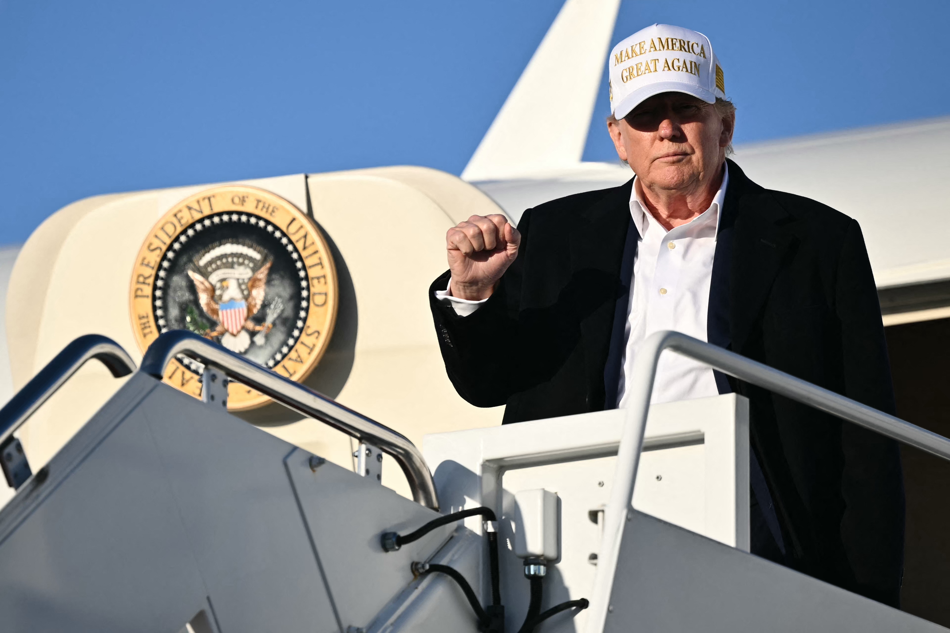 Donald Trump raising a fist as he steps off Air Force One upon arrival at Joint Base Andrews in Maryland on April 27, 2025. | Source: Getty Images