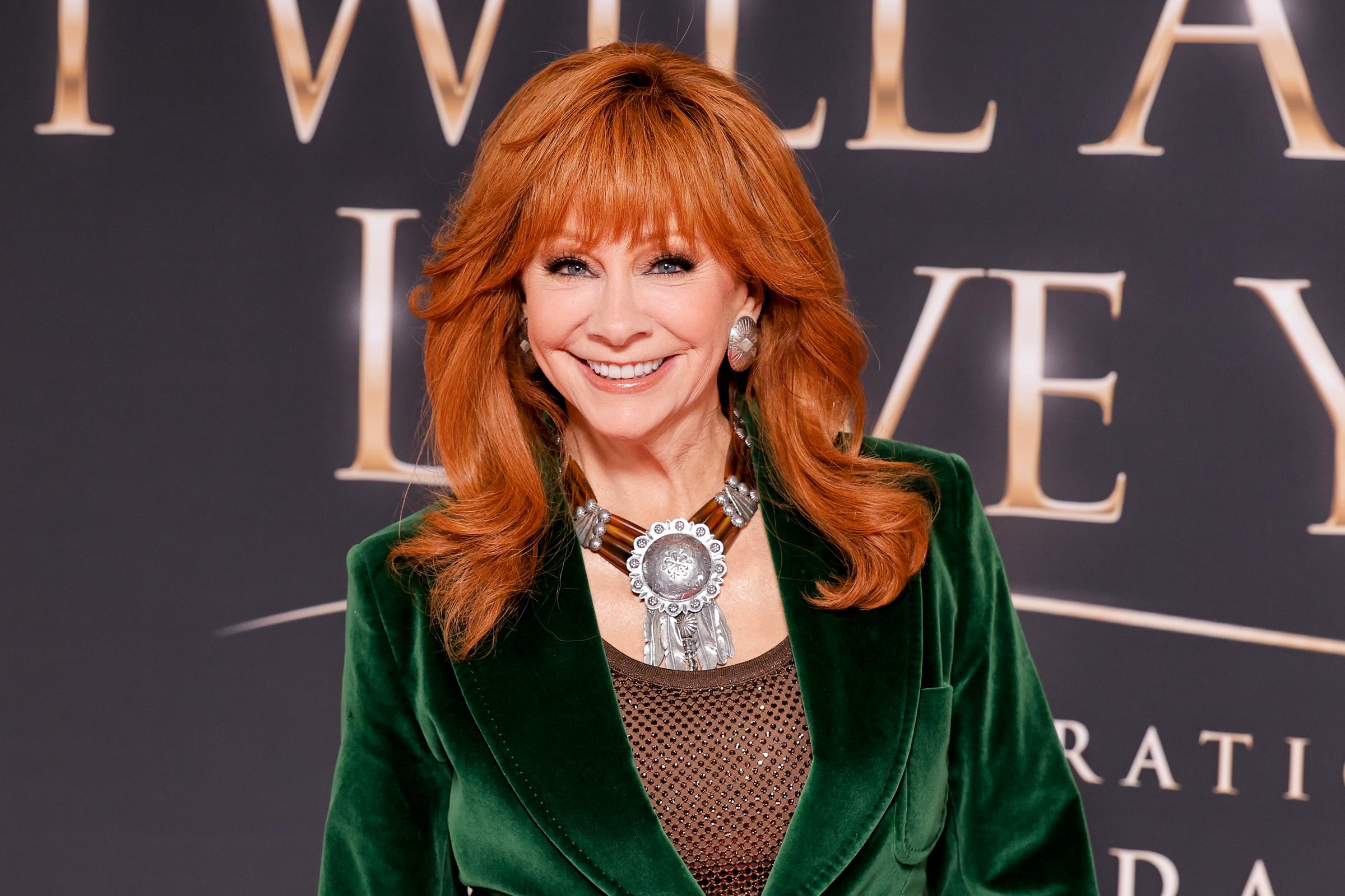 Reba McEntire flashes a wide smile as her statement silver jewelry and rich green velvet take center stage at the Dolly Parton tribute in Nashville on October 21, 2026. | Source: Getty Images