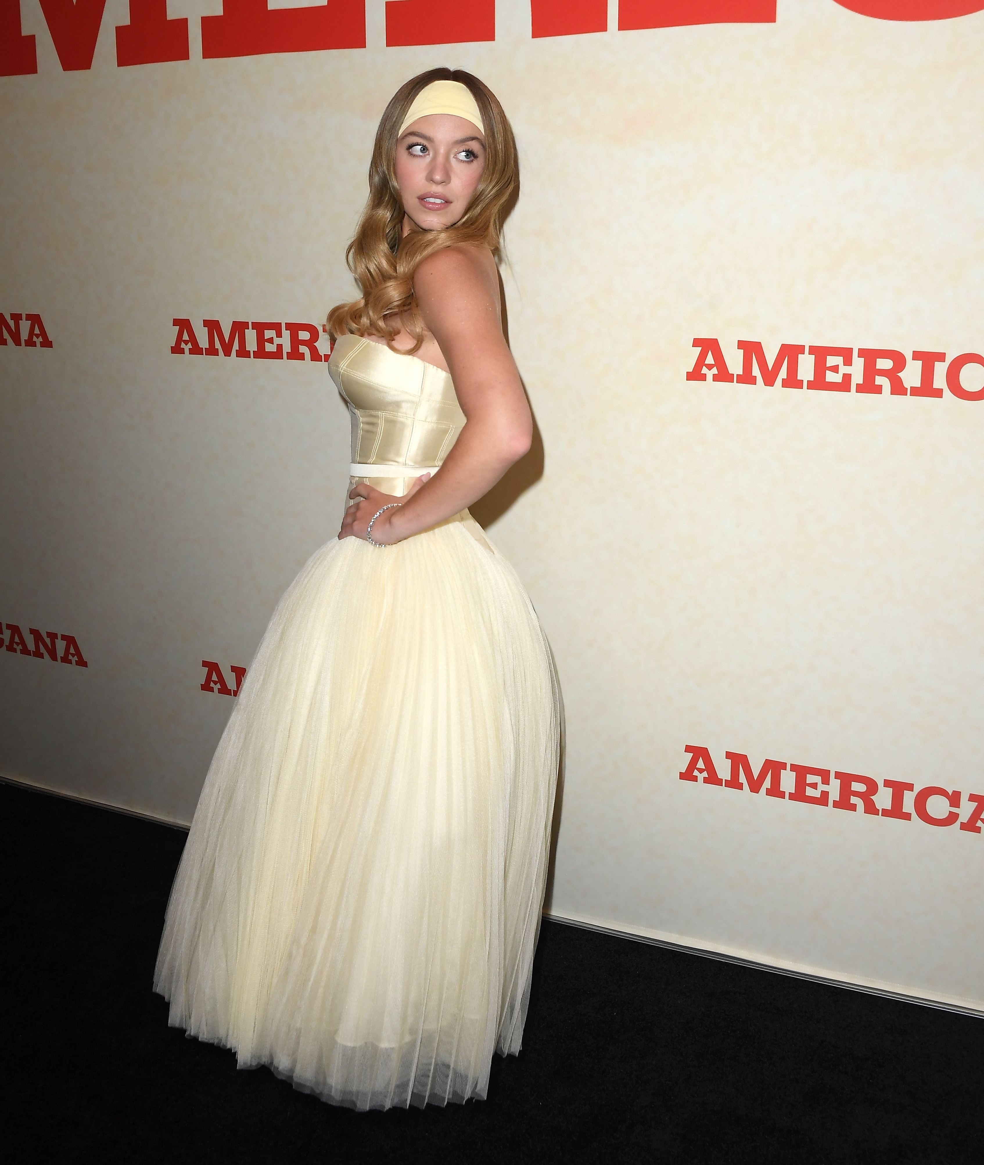 In this full-length shot, Sydney Sweeney's entire look comes into view. The dramatic ivory gown flows to the floor in layers of tulle, balanced by the fitted corset bodice.