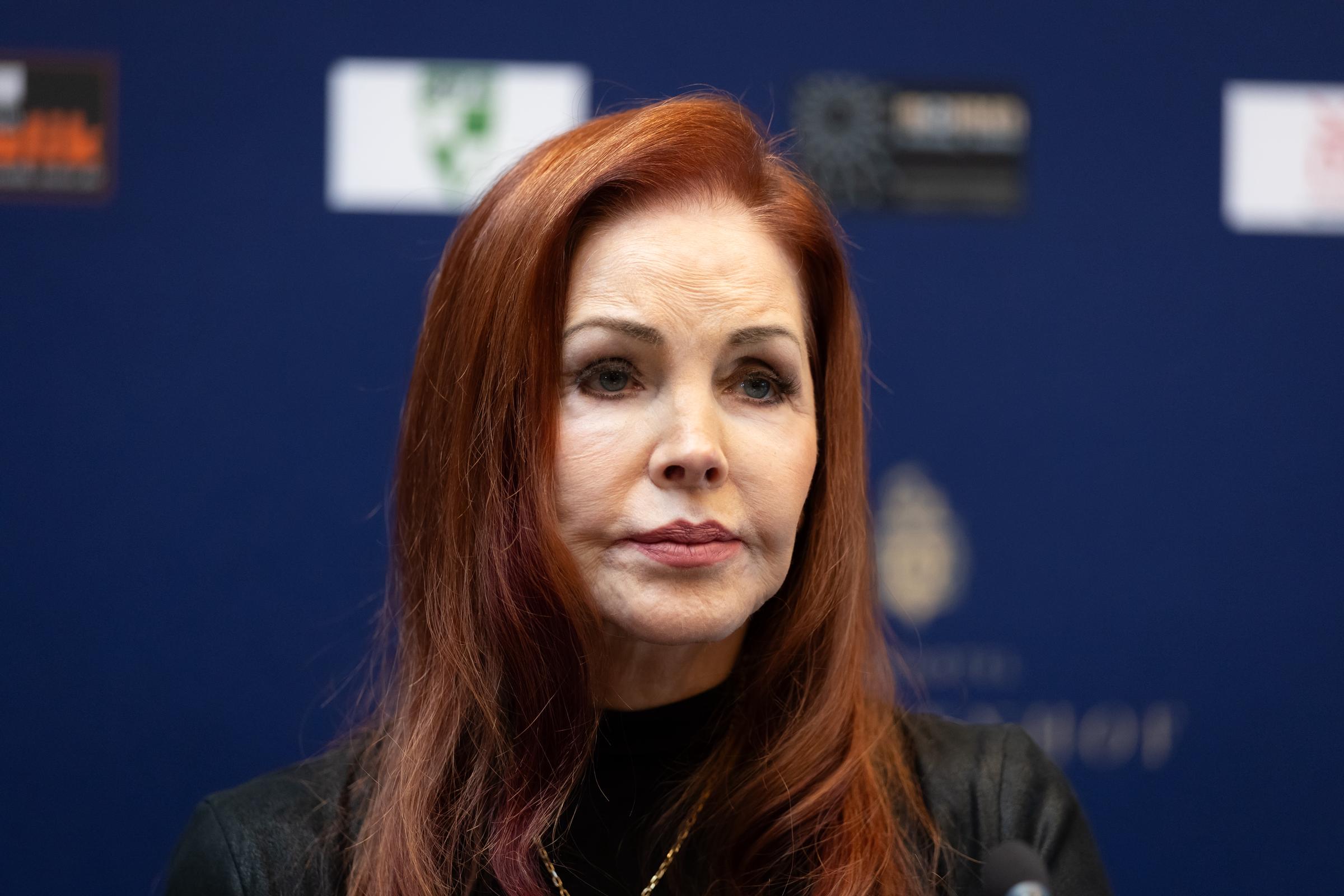 Priscilla Presley attends an event during a visit to Baesweiler, Germany, on October 20, 2026, wearing a black turtleneck top accented with a delicate gold necklace, with her signature auburn hair styled straight with a deep side part. | Source: Getty Images