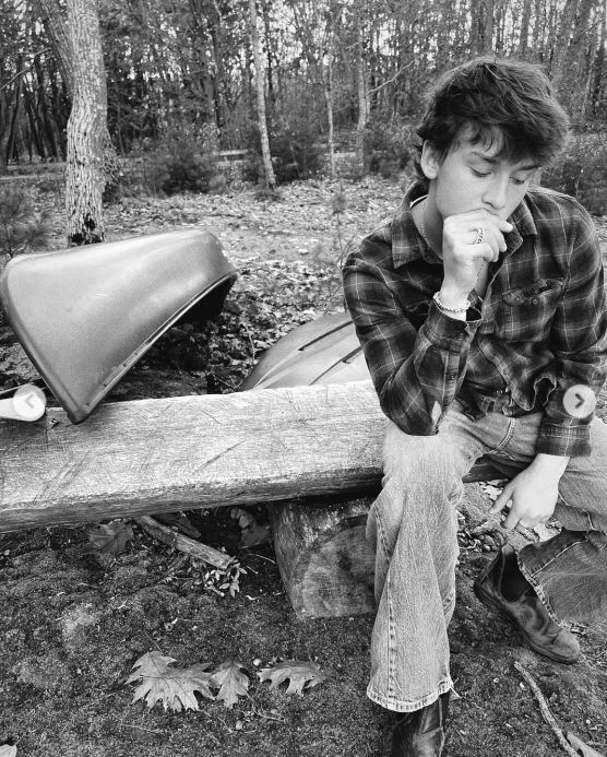 Darby Dempsey sitting on a bench with a canoe nearby, from a post dated November 26, 2025 | Source: Instagram/jilliandempsey