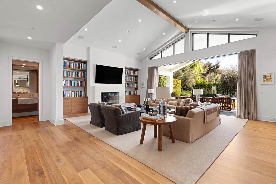 Books fill the built-in shelves surrounding the fireplace, giving this room a more lived-in quality than some of the home's formal spaces. The wide opening beside the seating area also places the covered patio only steps away. | Source: Instagram/theshevins
