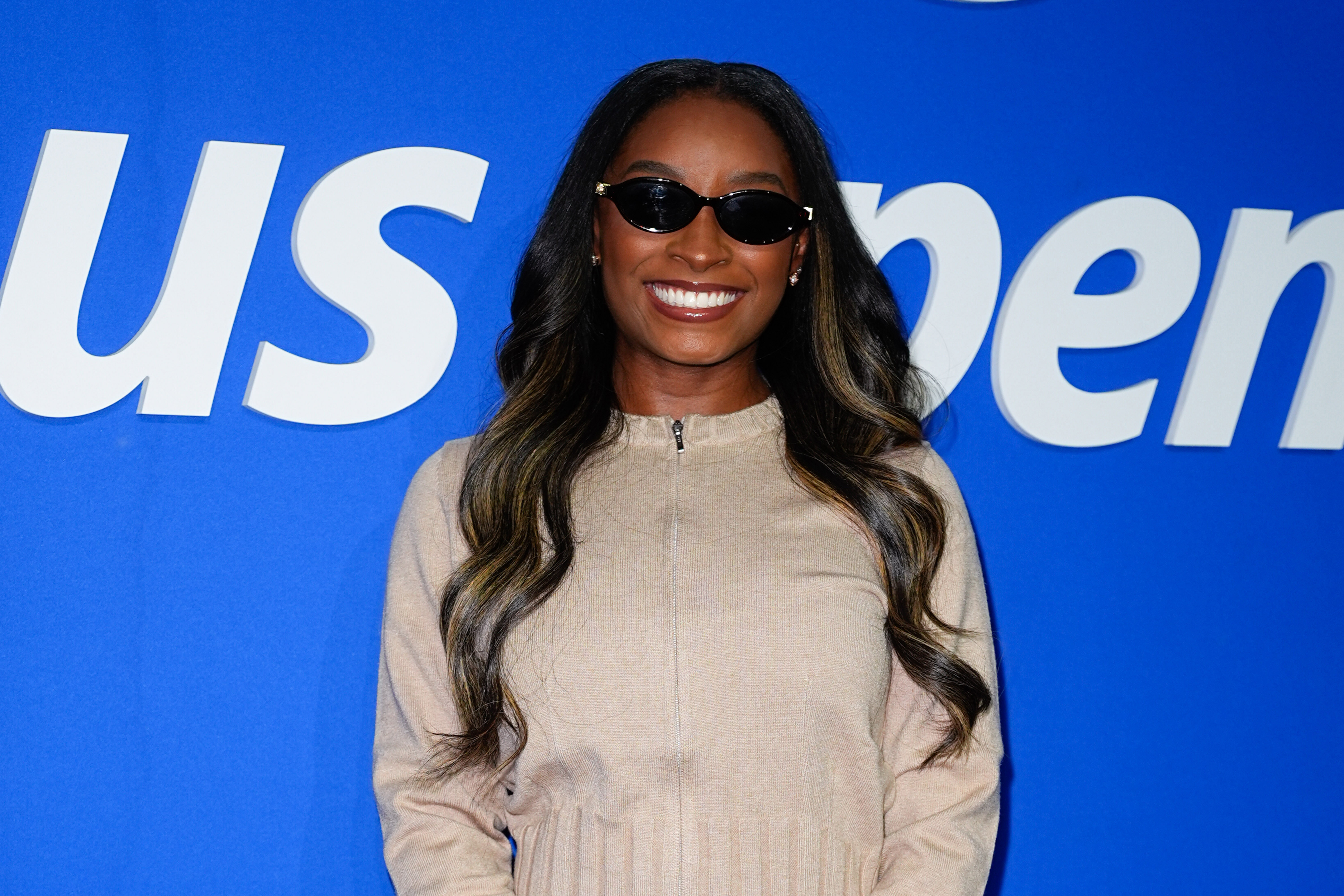 Attending Day 10 of the tournament on September 8, 2026, Biles opted for a coordinated neutral-toned ensemble. She wore a fitted beige knit zip-front top with long sleeves, paired with a matching cream mini skirt. | Source: Getty Images