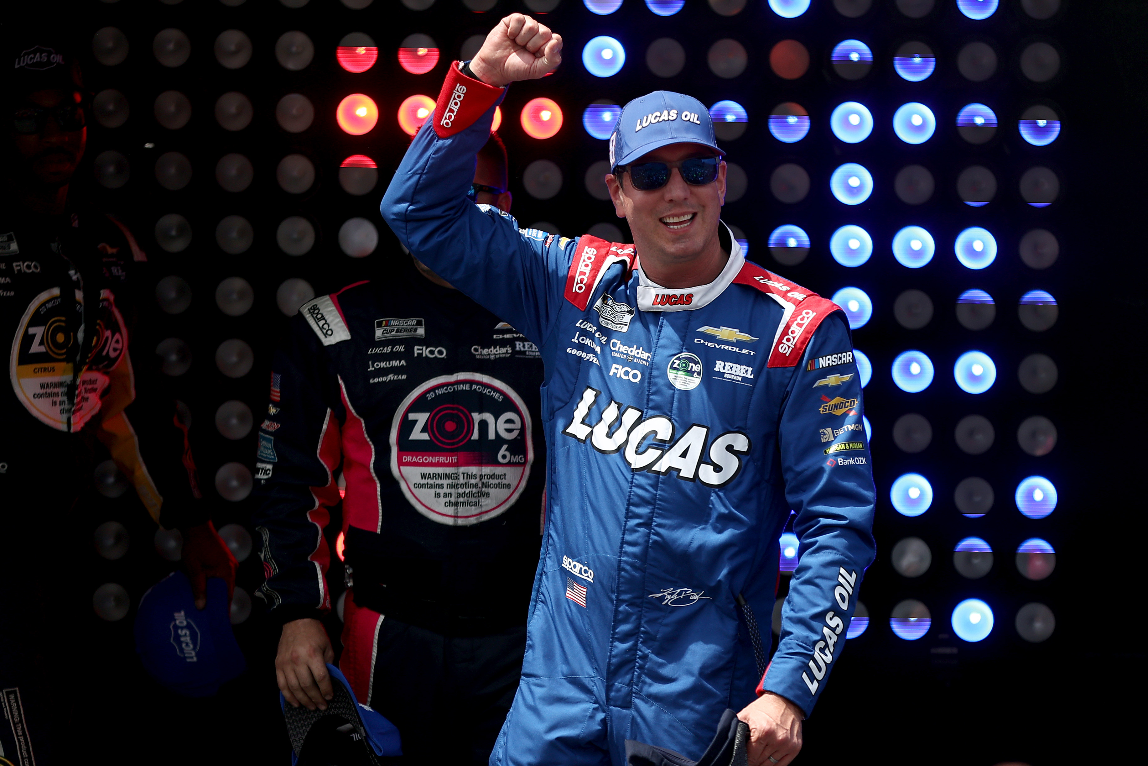 Kyle Busch smiles and lifts his arm prior to the NASCAR Cup Series All-Star Race. | Source: Getty Images