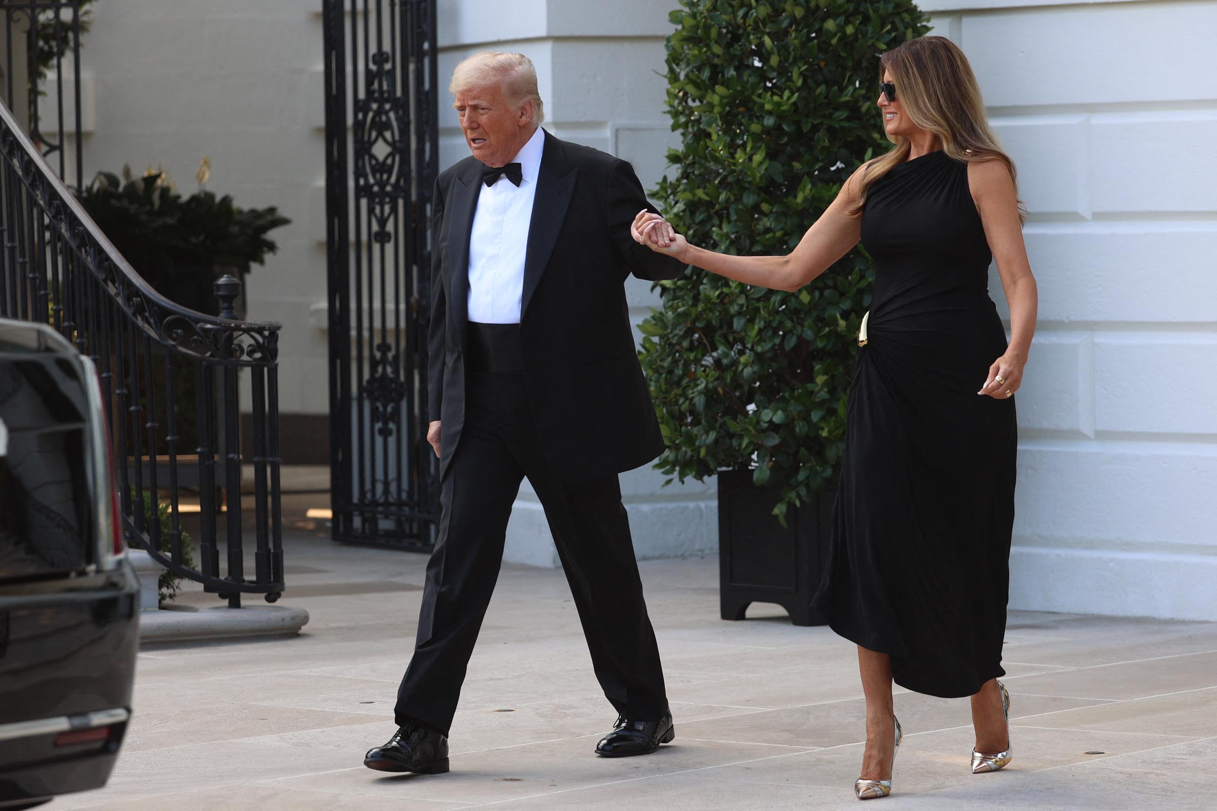 The president appears to speak as he leads the first lady toward their motorcade, while she looks on with a slight smile — capturing a candid moment outside the White House on June 11, 2025.