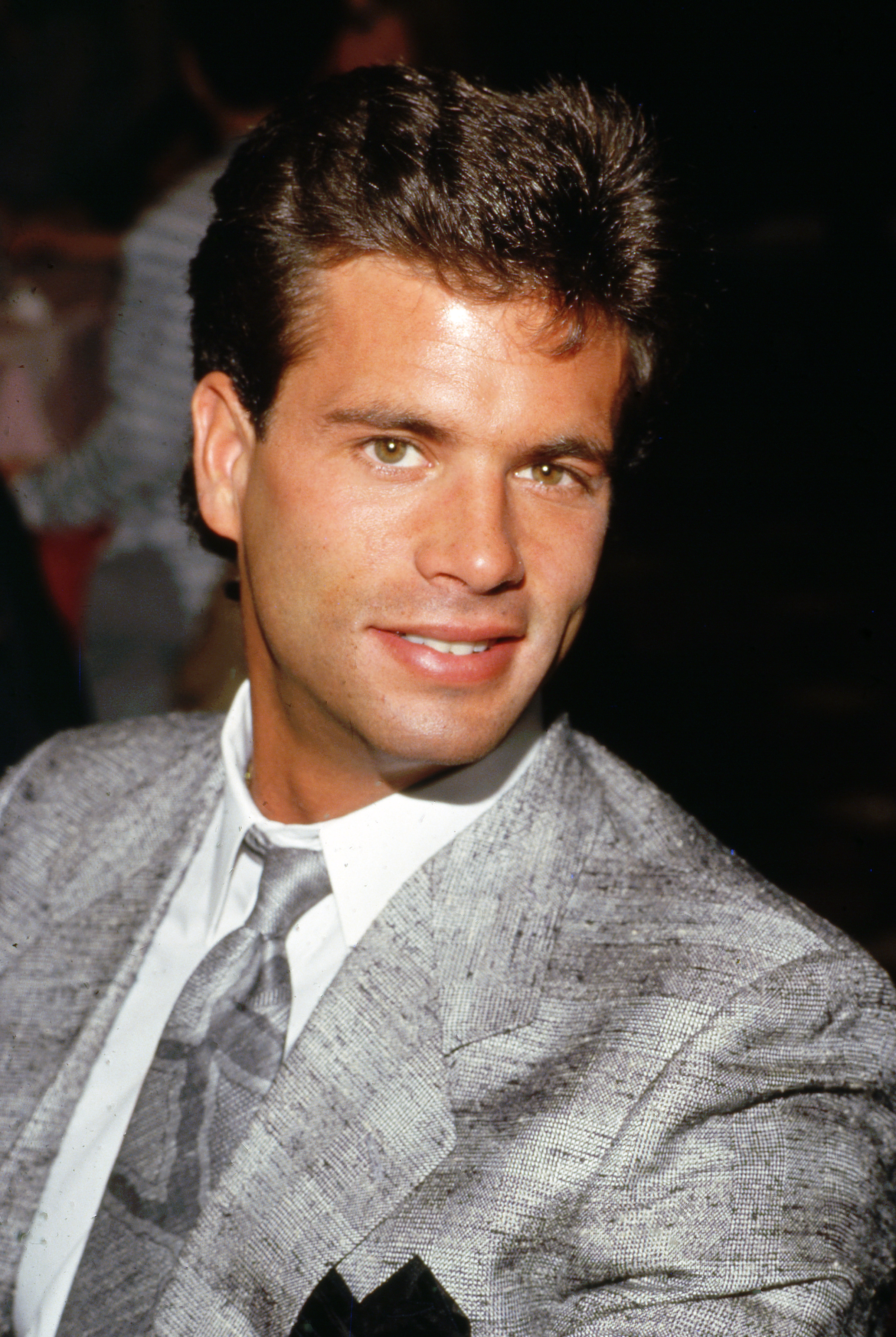 During the 1980s, Lorenzo Lamas was photographed sporting the thick dark hair and clean-cut style closely associated with his heartthrob years. Wearing a gray patterned suit and coordinating tie, the actor smiled for the camera as his profile in entertainment continued to grow. The image preserved another glimpse of the polished public persona he carried during one of the defining decades of his television career.