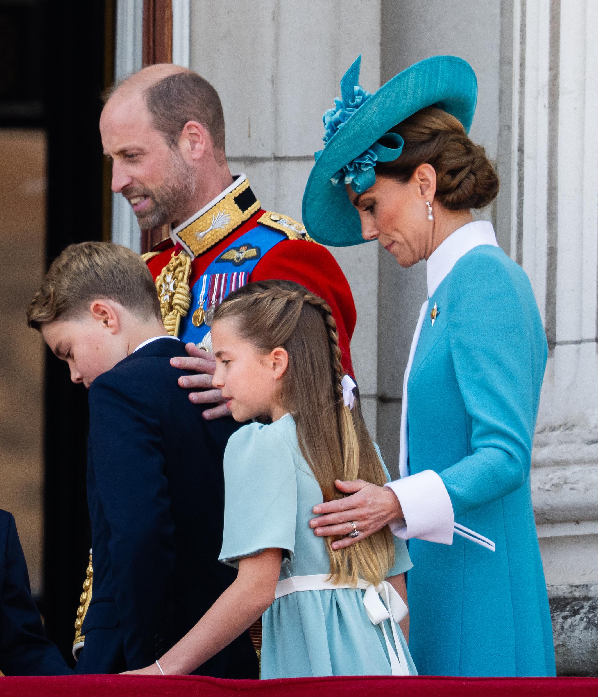 In a three-quarter shot taken during the 2025 Trooping the Colour, Prince William and Princess Catherine stand with their children—Prince George, Princess Charlotte, and Prince Louis—capturing a unified and graceful family presence. Dressed in coordinated formal attire, the family appears composed and attentive, reflecting their central role in the day’s ceremonial observances.