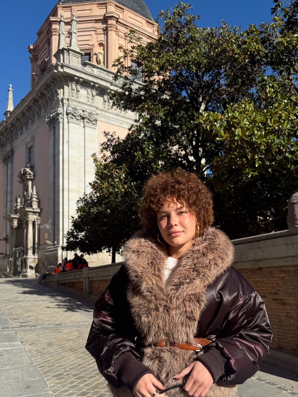 Isabella Strahan poses in Madrid wearing a fur-trimmed coat and natural curls, as posted on December 2, 2025 | Source: Instagram/isabellastrahan