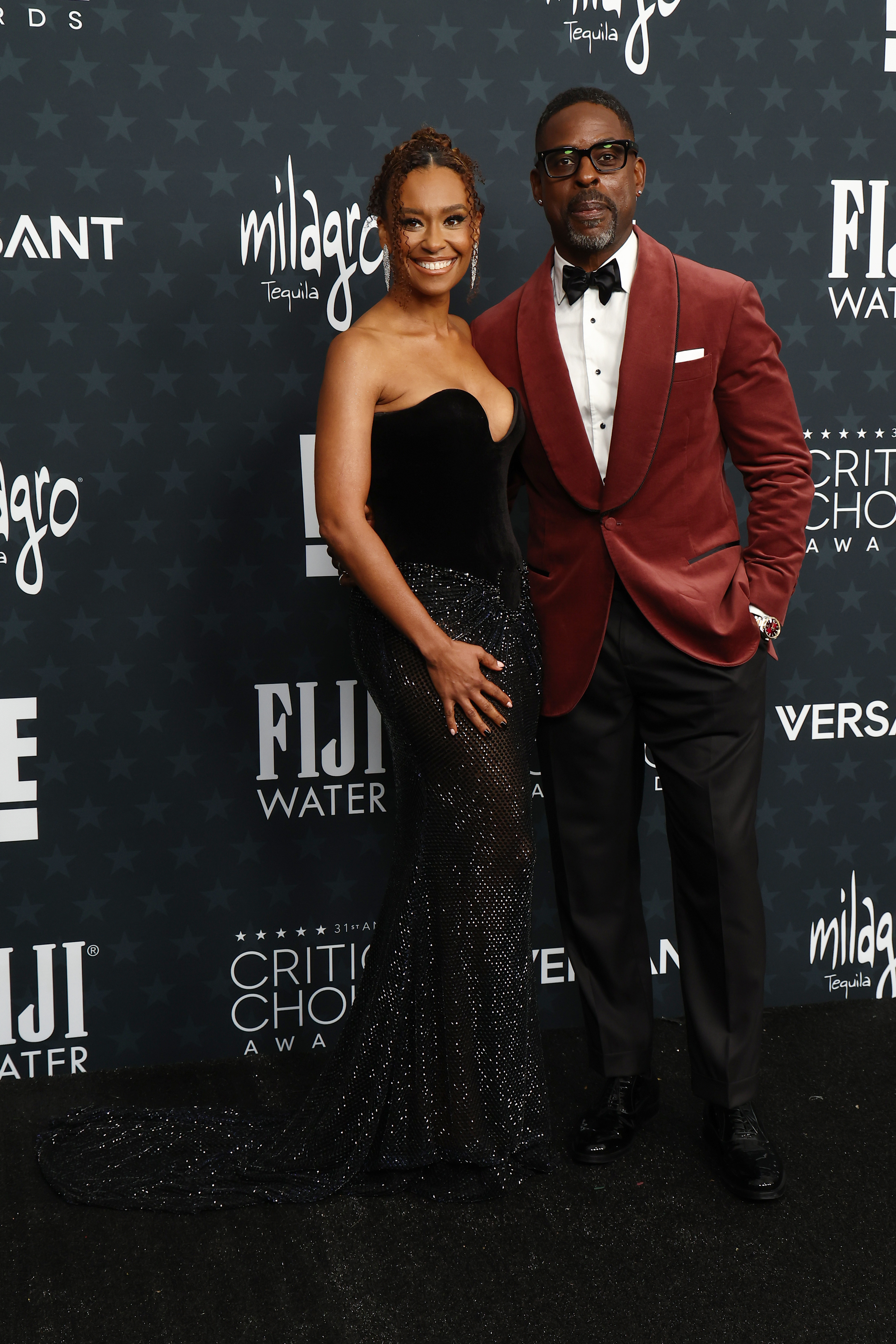 Ryan Michelle Bathe and Sterling K. Brown arrive in elegant style, she in a glittering black gown and he in a wine velvet jacket | Source: Getty Images