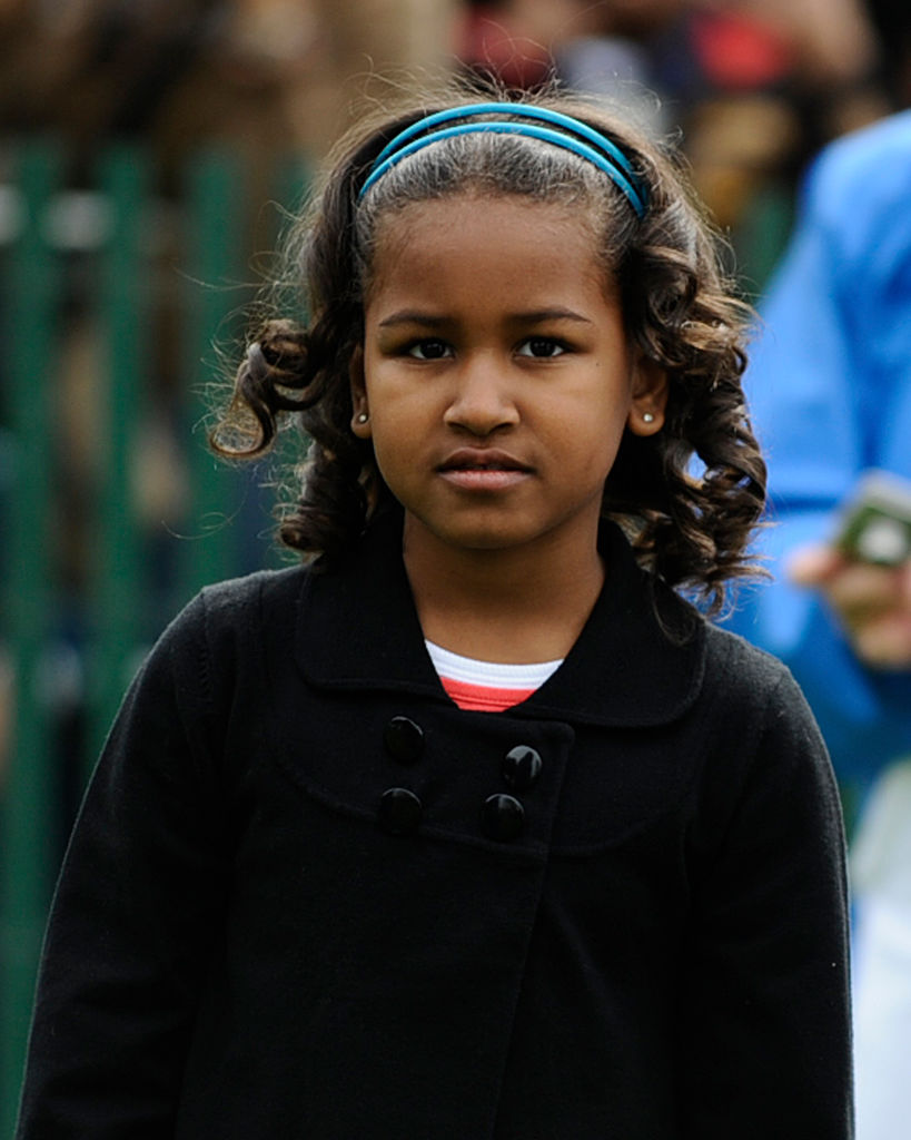 While attending the White House Easter Egg Roll on April 13, 2009, in Washington, D.C., Sasha — dressed in a black coat and blue headband —stood with a composed gaze as she observed the event from the South Lawn among guests and cameras.