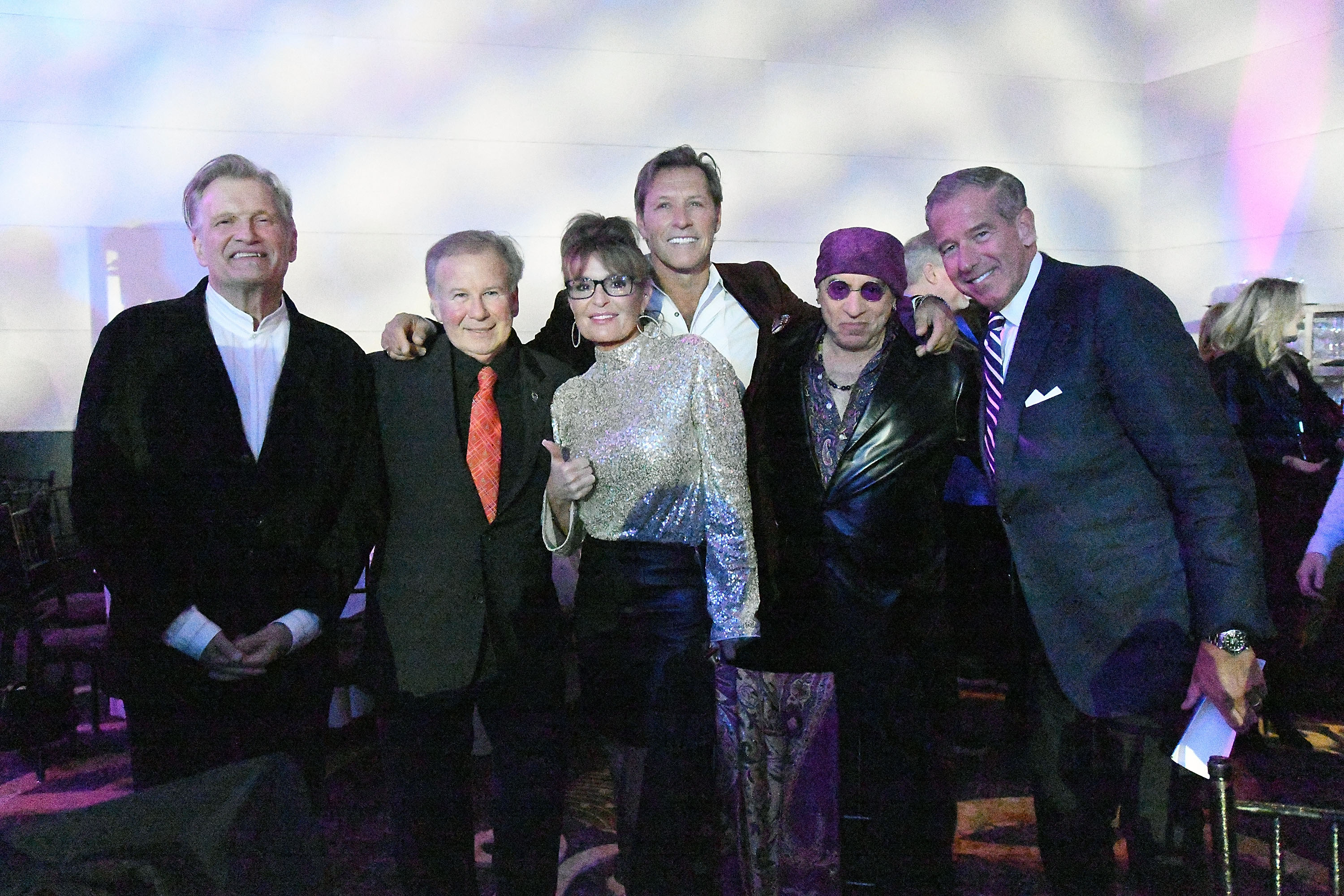 Ron Duguay smiles alongside his girlfriend, Sarah Palin, and other guests at Little Steven's Policeman's Ball in New York City on December 21, 2023. The photo captures a happy moment from their relationship, which Palin had described as a source of comfort and support. | Source: Getty Images