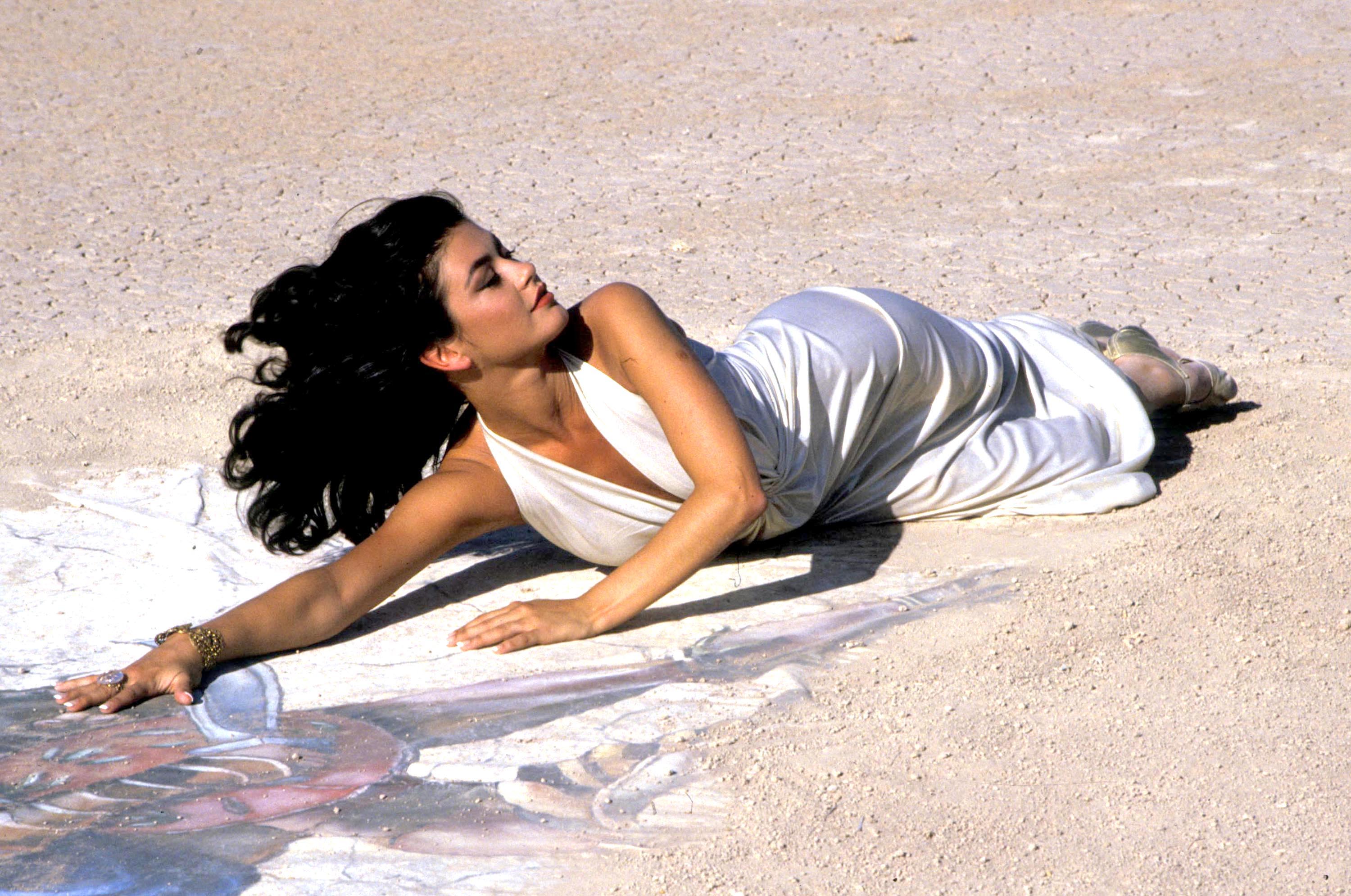 In this early-career photograph, Catherine Zeta-Jones posed in a flowing white dress with her long, dark hair loose, years before "The Mask of Zorro" established her as one of Hollywood's most celebrated beauties. | Source: Getty Images