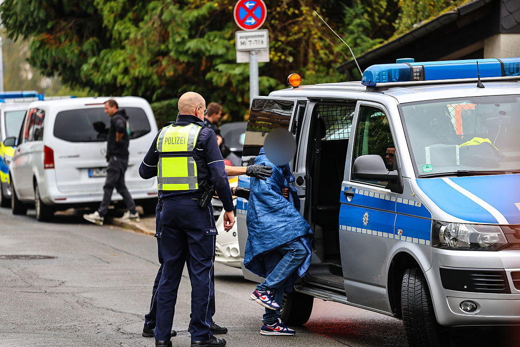October 07, 2025, North Rhine-Westphalia, Herdecke: Police officers bring a teenager into a police car. The newly elected mayor of Herdecke, Iris Stalzer (SPD), has been found seriously injured in her apartment. According to security sources, she had been stabbed several times | Source: Getty Images