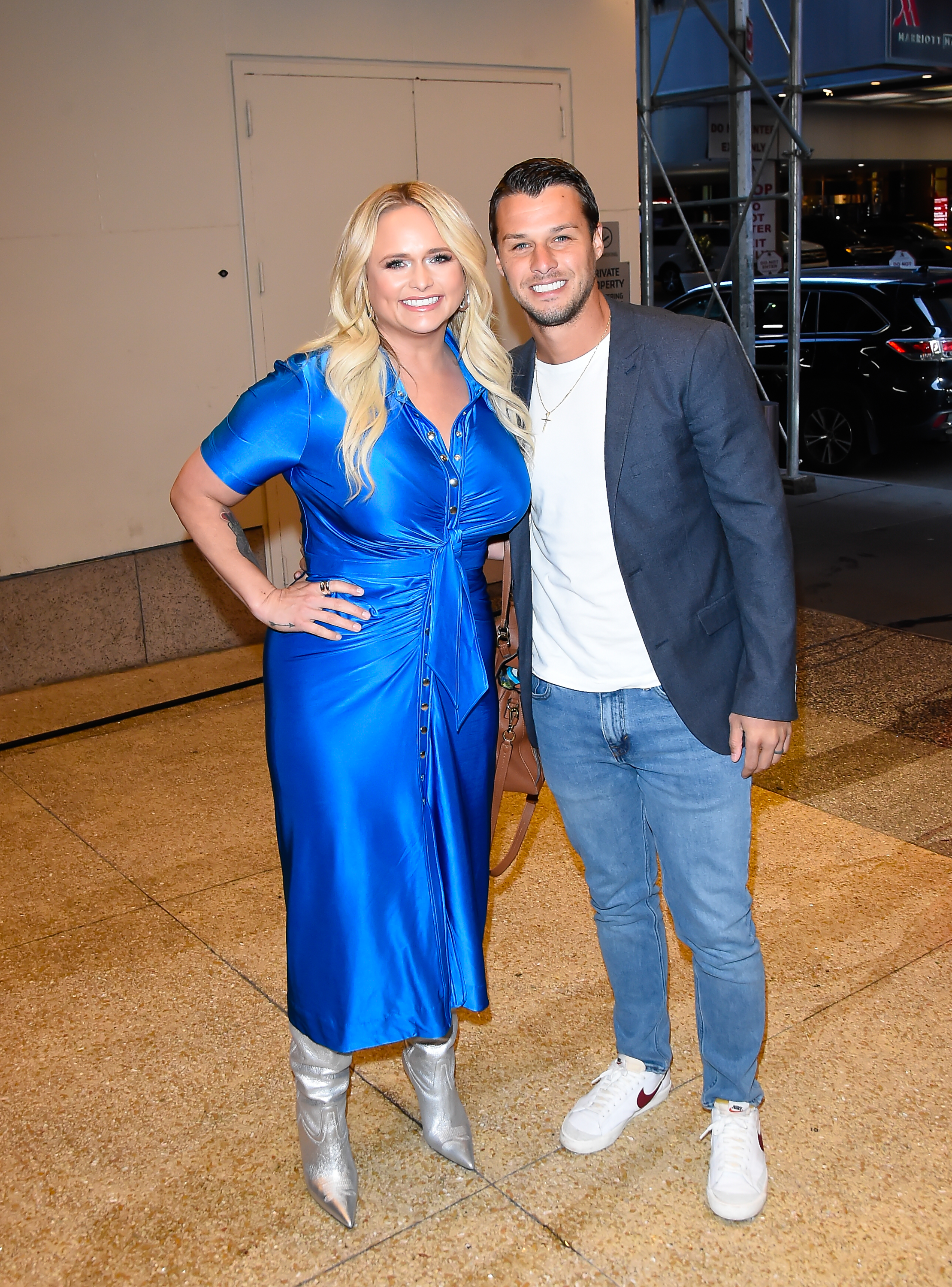 Miranda Lambert and husband Brendan McLoughlin stepped out in style outside CBS Studio on April 25, 2023, in New York City. The country star turned heads in a vibrant royal-blue satin shirt-dress styled with metallic silver boots, while McLoughlin kept it smart and laid-back beside her in a dark navy blazer, white tee, light-wash denim, and white sneakers. | Source: Getty Images