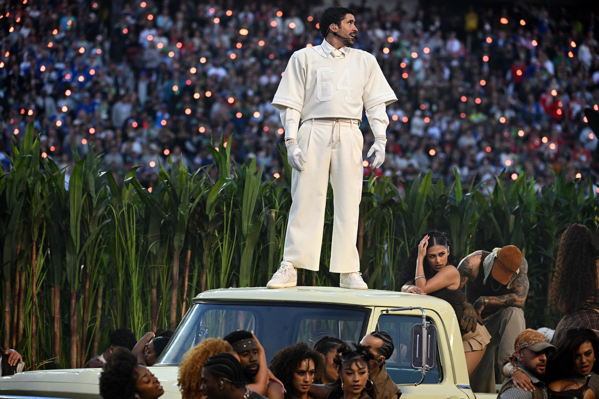 Bad Bunny stands atop a vehicle during his performance while surrounded by dancers, captured in a dynamic moment from the halftime show. | Source: Getty Images