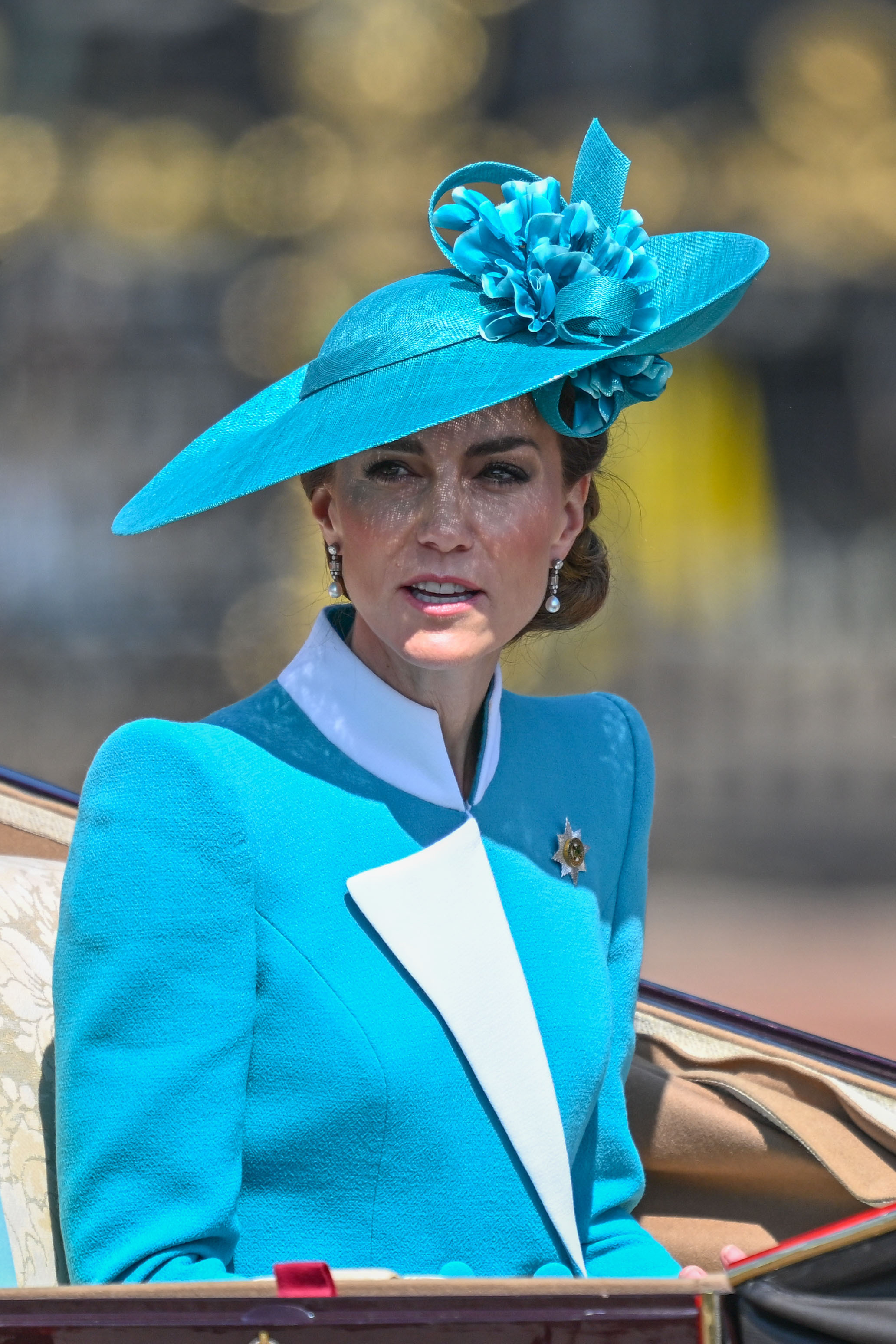 In this medium shot, Princess Catherine is seen in her teal and white ensemble during the 2025 Trooping the Colour. The design of her structured blazer is clearly visible, with bold white accents at the collar and cuffs adding contrast to the rich teal fabric. Poised and composed, she exemplifies modern royal elegance.