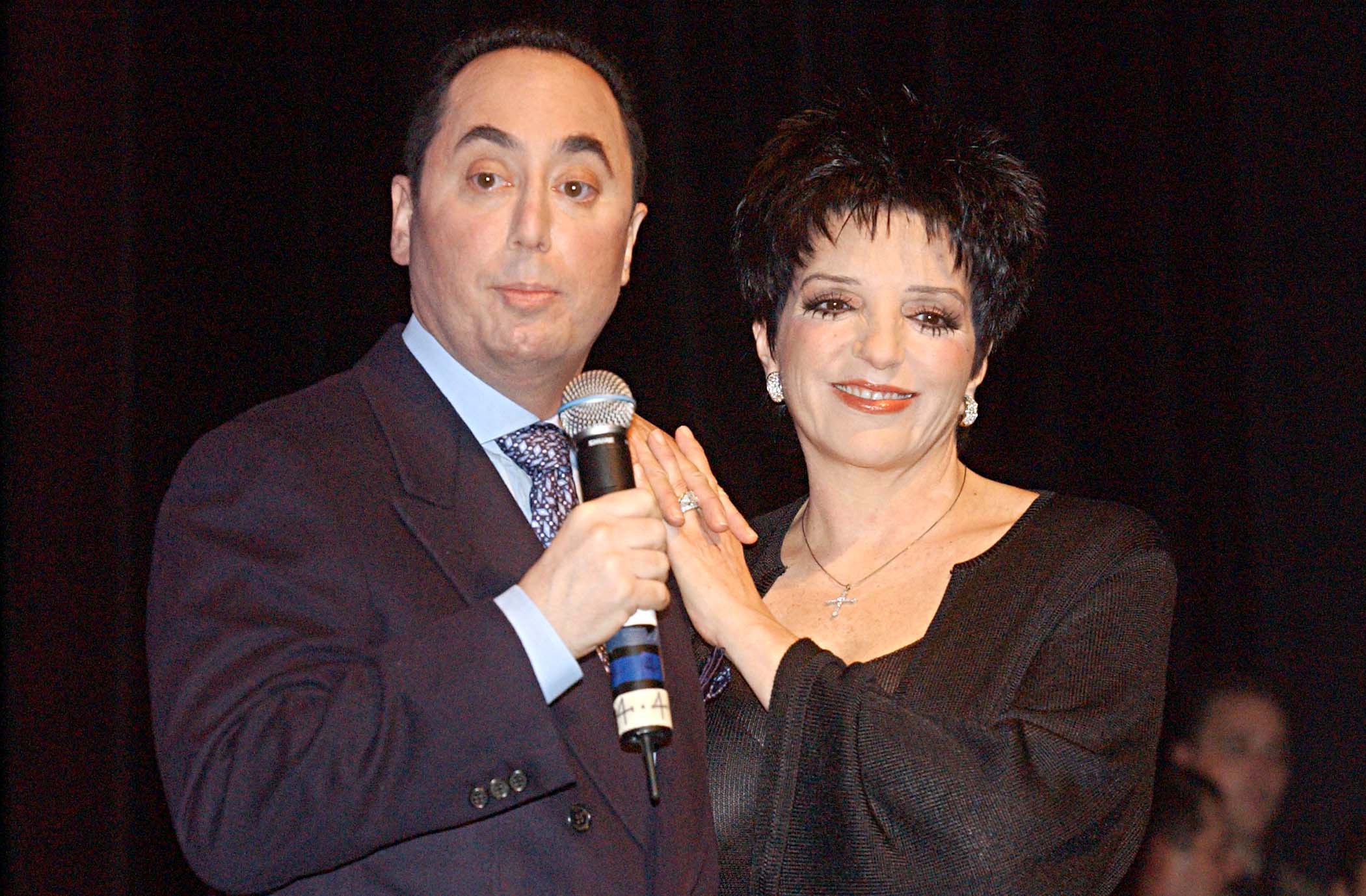 David Gest stood alongside his then-wife, Liza Minnelli, during a press conference at the House of Blues in West Hollywood, California, on July 25, 2002. With Gest holding a microphone and Minnelli resting her hands on his shoulder, the newlyweds posed together as they announced plans to star in a weekly musical reality series for VH1, bringing their personal and professional partnership before the cameras.