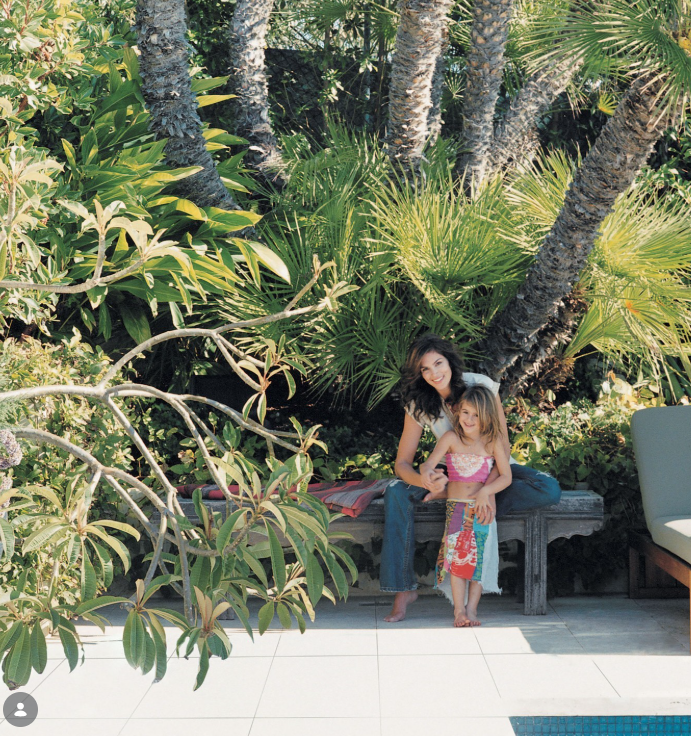 Cindy sits with a young Kaia beside the pool at the family's Malibu home. Cindy said the outdoor spaces became part of everyday family life while the children were growing up. | Source: Instagram/elledecor