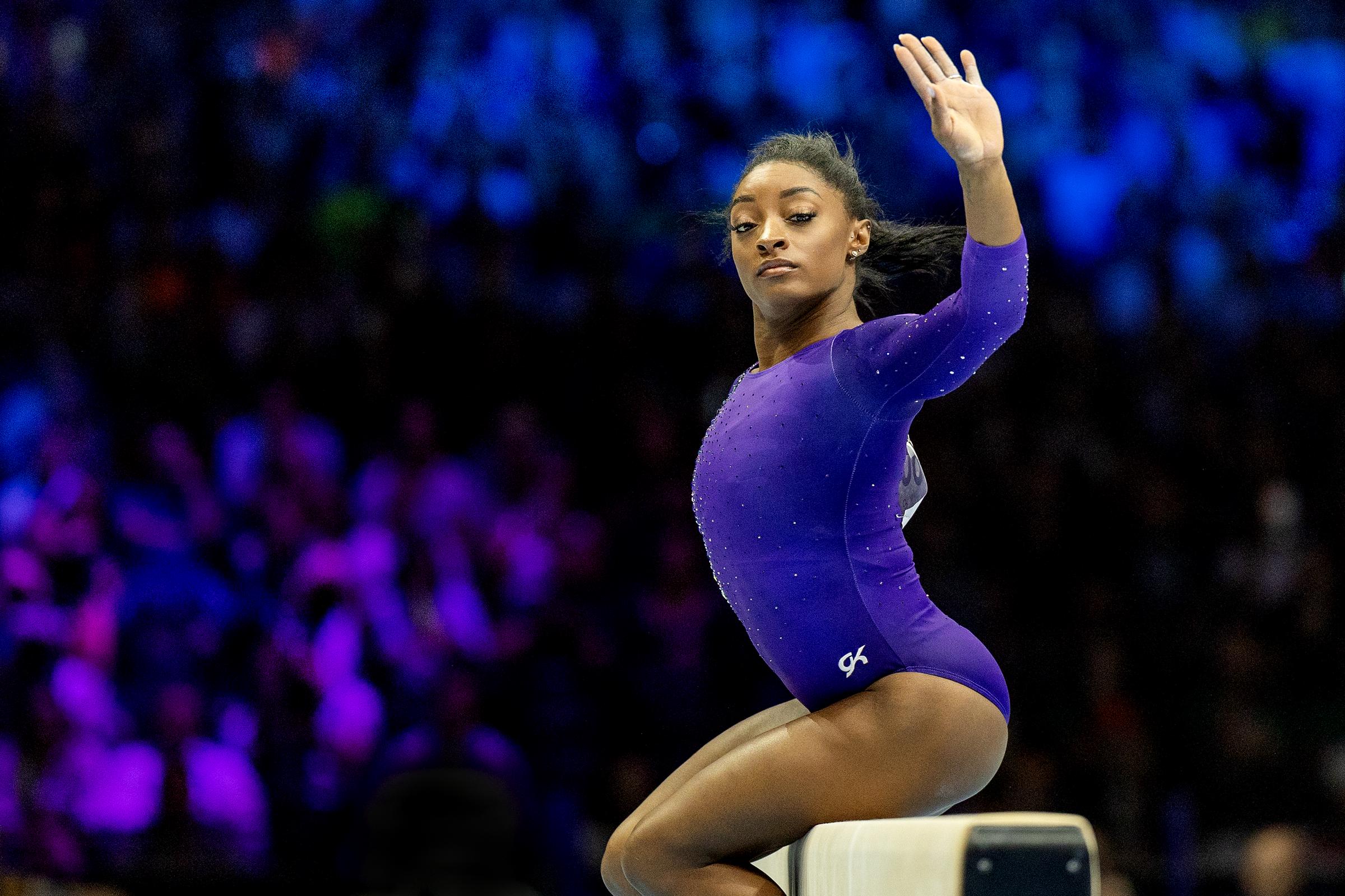 Frozen in motion, Simone Biles strikes a dramatic pose on the balance beam, her eyes locked in fierce focus during her gold-winning routine in Antwerp on October 8, 2023.