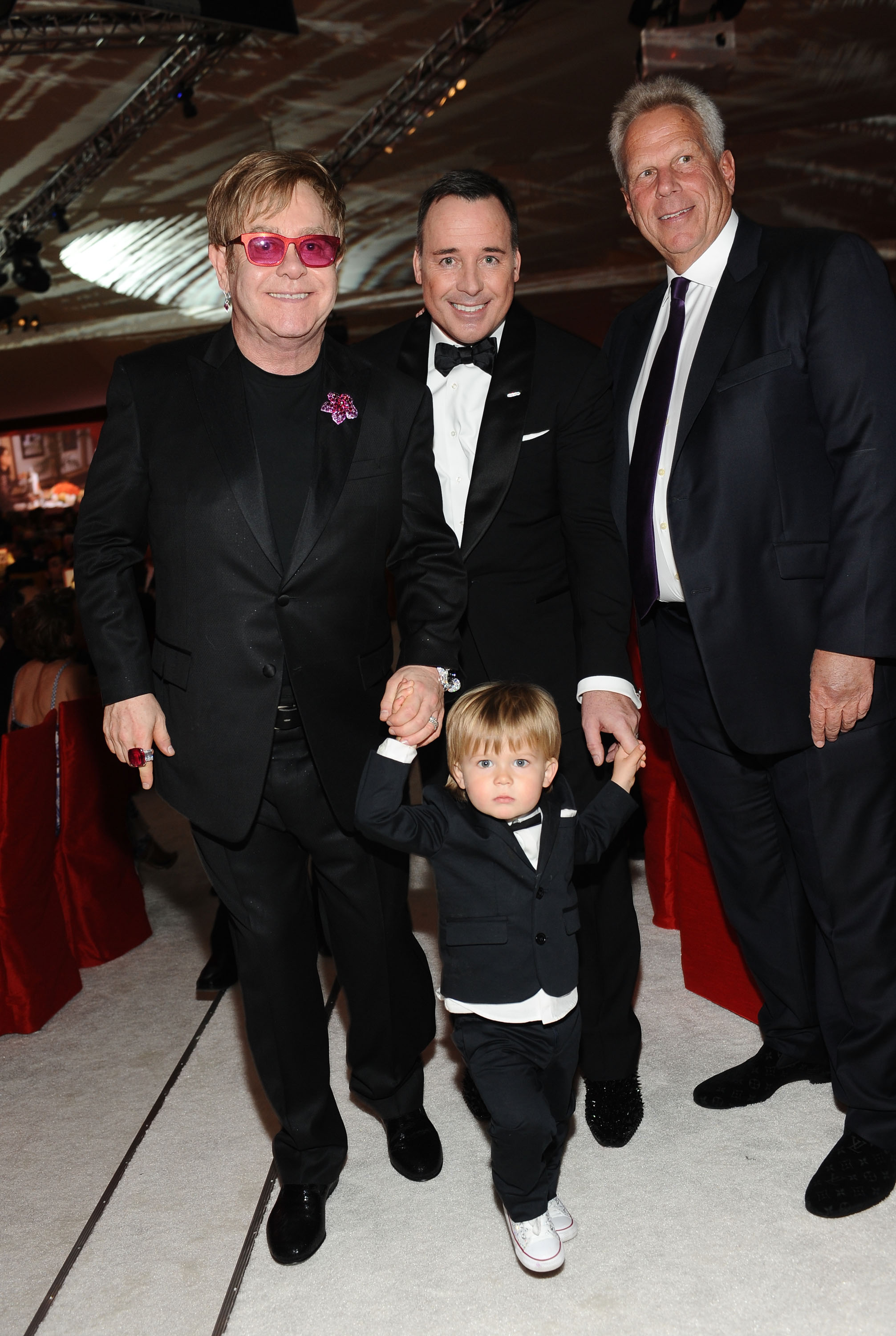 Sir Elton John and David Furnish with their sons, Zachary Furnish-John, and Chairman and Executive Vice President of the New York Giants, Steve Tisch, at Chopard at the 21st Annual Elton John AIDS Foundation Academy Awards Viewing Party on February 24, 2013, in West Hollywood, California. | Source: Getty Images
