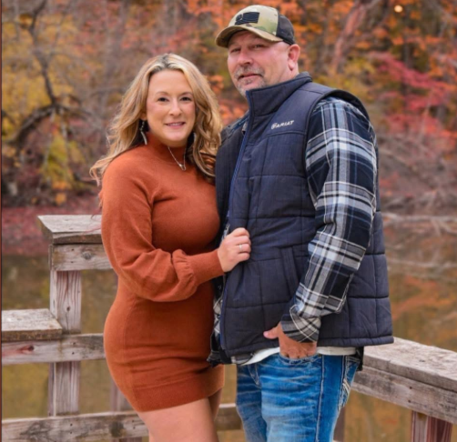 Rachel and her husband Jeremy Tussey stands close on a wooden bridge, framed by rich autumn colors reflected in the still water behind them. | Source: GoFundMe