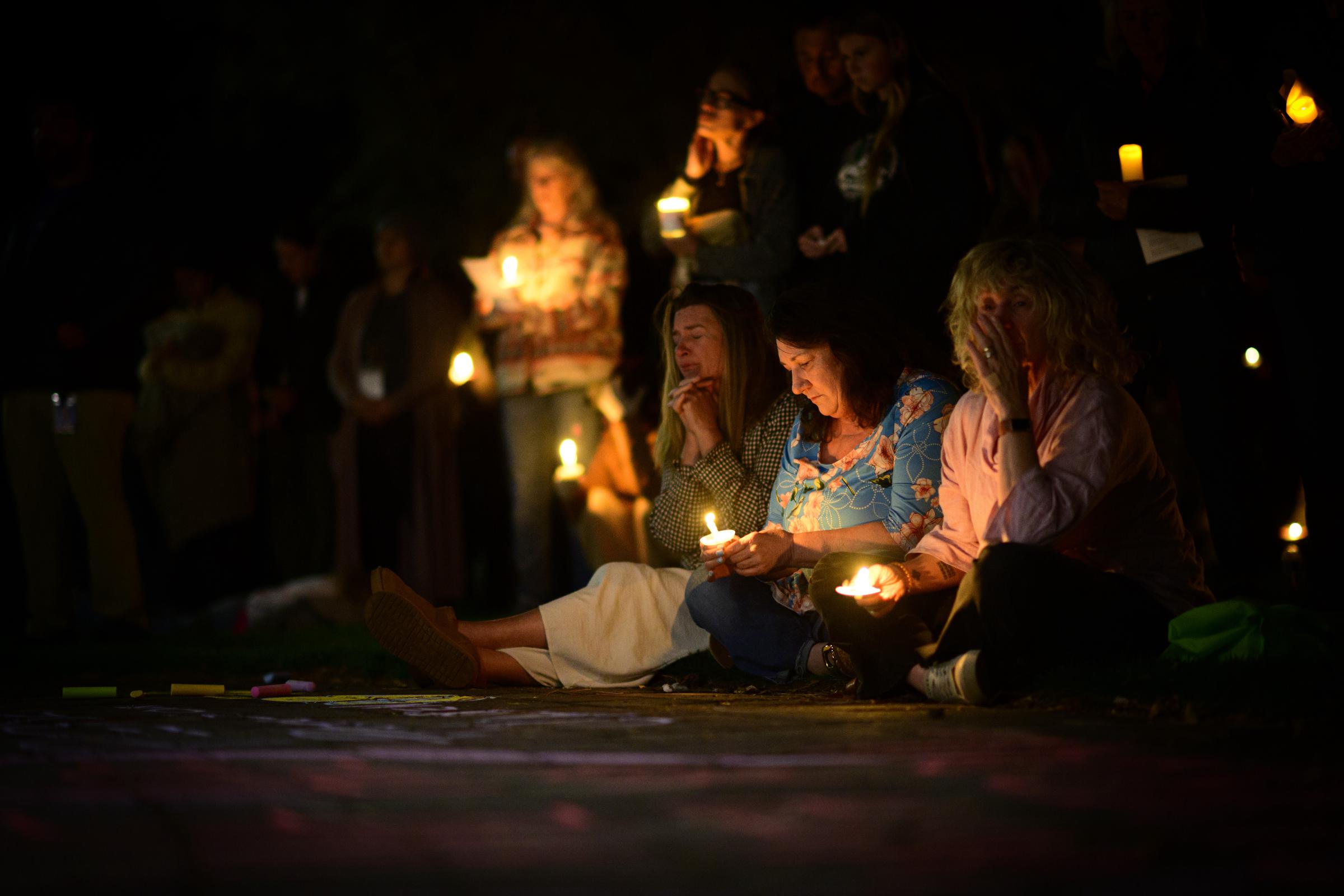 Candle-holding mourners sit together during a community gathering held in the aftermath of the deadly elementary school shooting. | Source: Getty Images