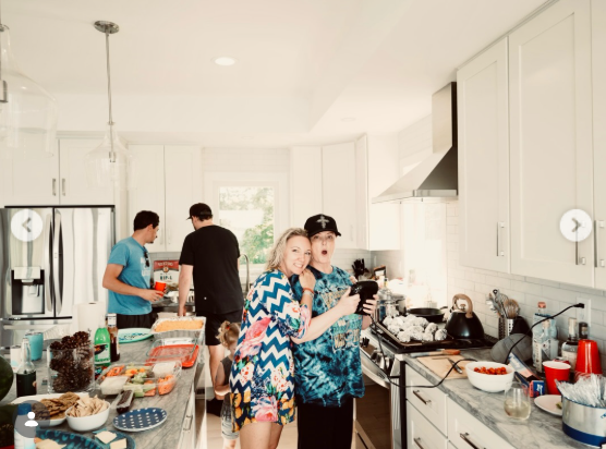 Several people gather around the counters and stove in a bright kitchen filled with food and serving dishes. The photograph captures the activity of a shared meal rather than a formal room display. | Source: Instagram/wynonnajudd