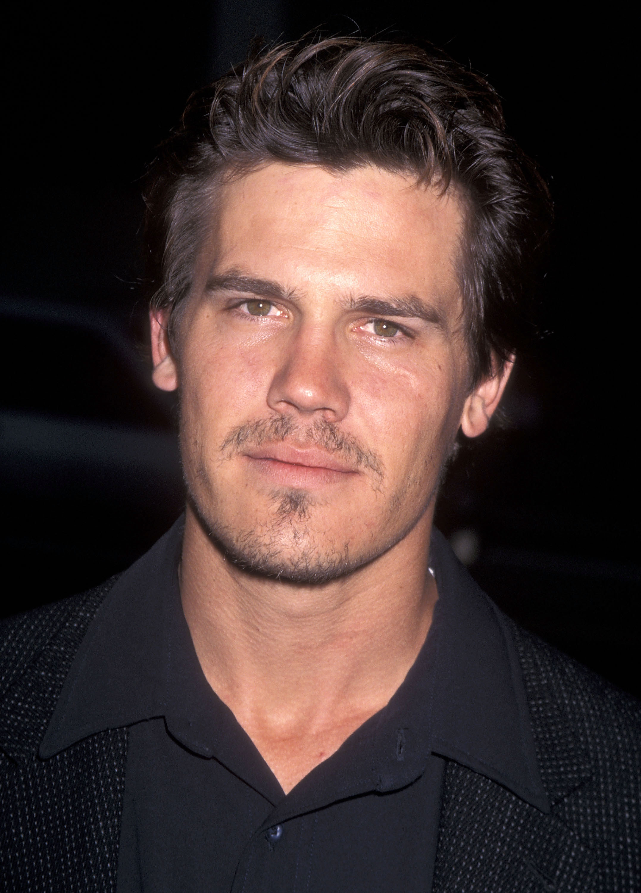 Brolin steps onto the red carpet for the "I Shot Andy Warhol" premiere, his expression cool and unreadable. With tousled hair, a dark shirt, and a hint of a goatee.