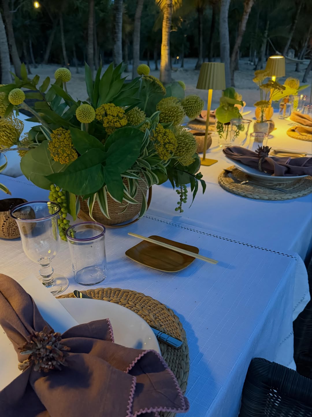 Soft lighting and lush tropical centerpieces set the mood for an intimate evening gathering beneath the palm trees. | Source: Instagram/bettinatrump