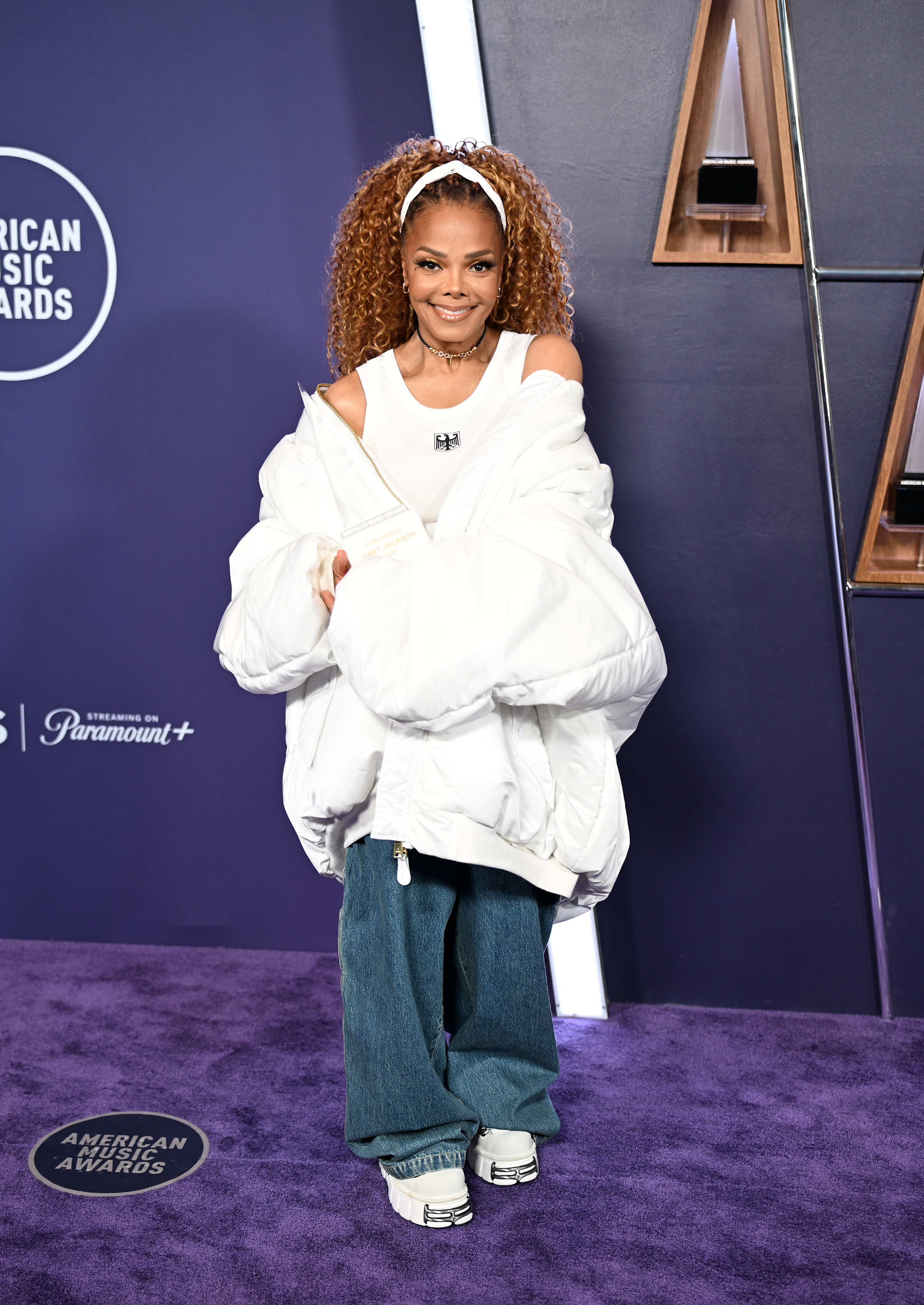Her fresh-faced glam and confident stance radiate joy as she poses in head-to-toe white against the AMA press wall.