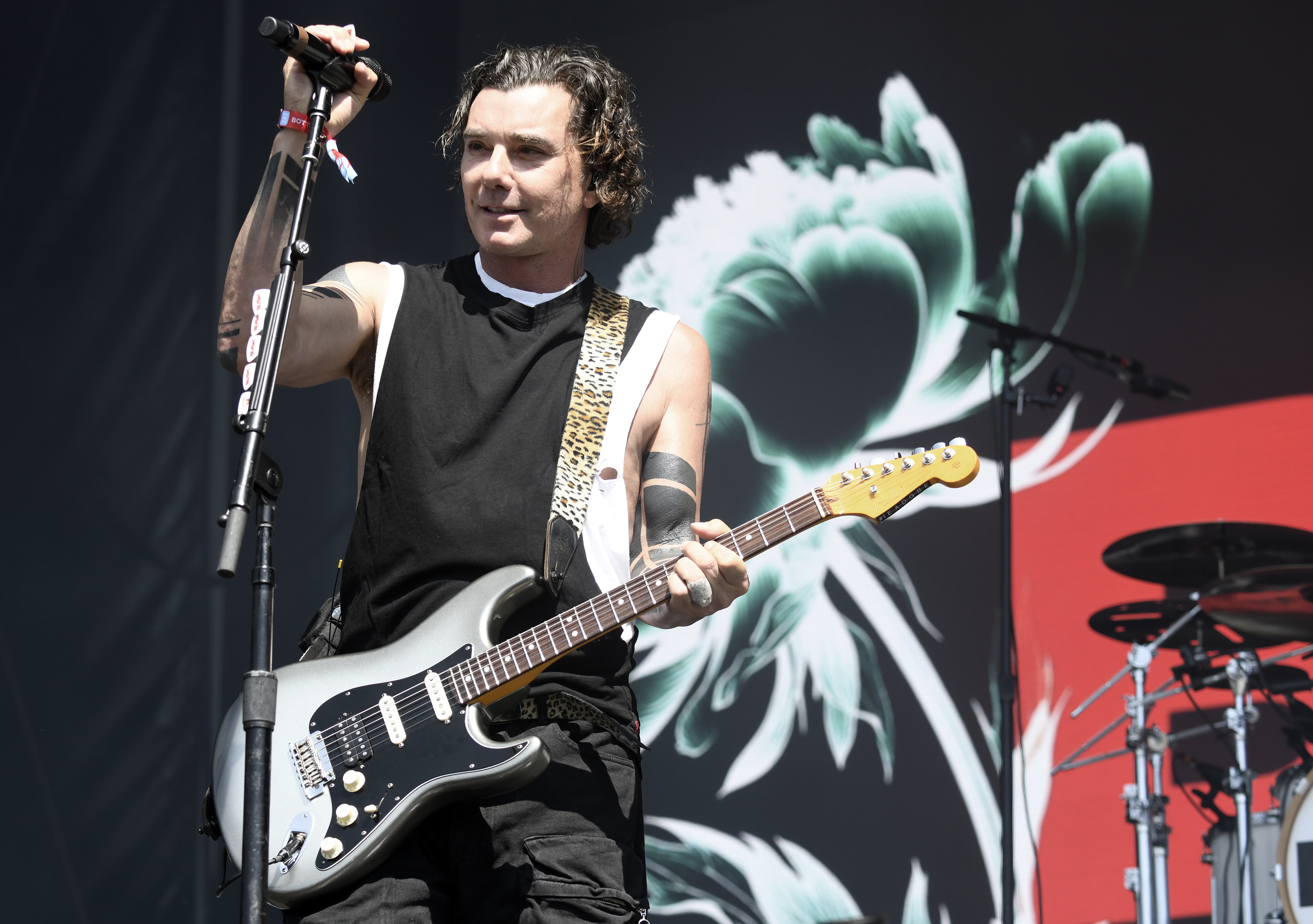 Gavin Rossdale performs with Bush at the BottleRock festival in Napa, holding a black electric guitar while wearing a sleeveless top that shows his arm tattoos.