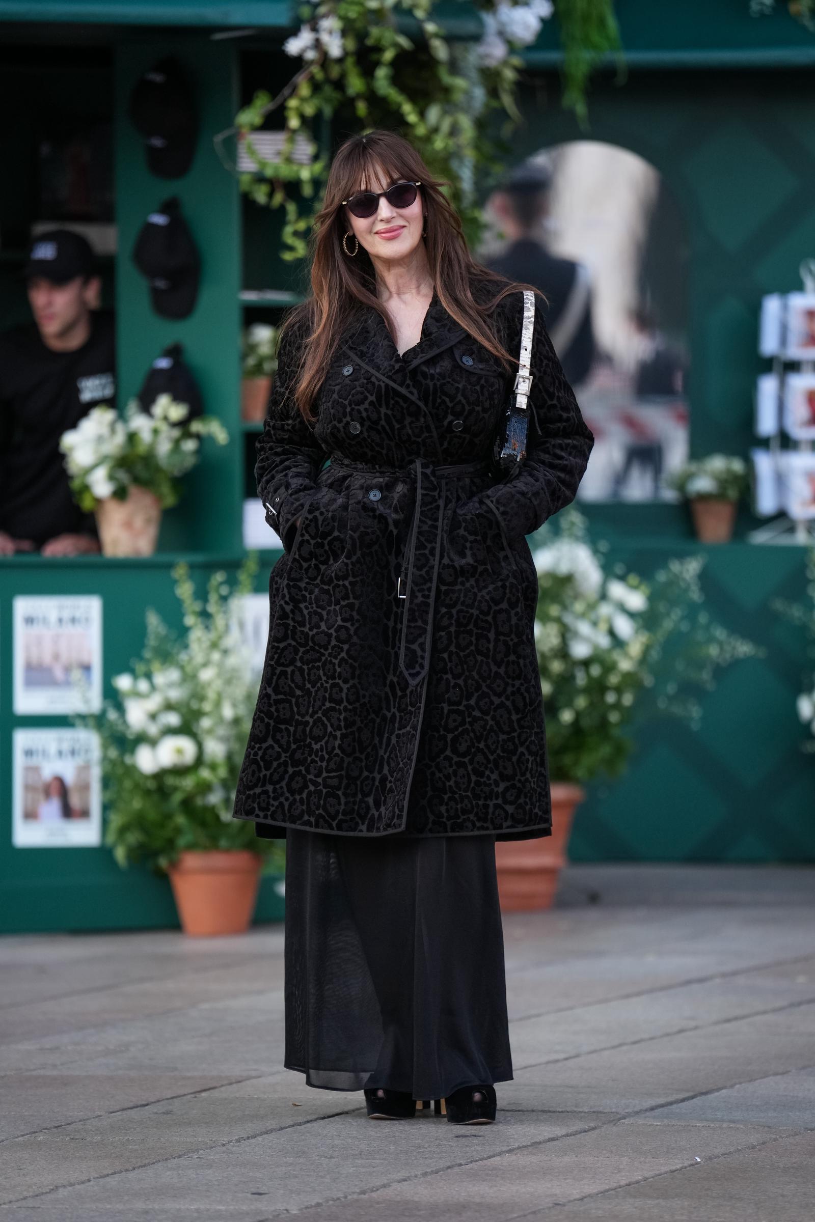Outside the runway venue, she posed in a striking all-black ensemble ahead of the Womenswear Spring/Summer 2027 shows on September 22, 2026, in Milan, Italy. She layered a belted black animal-jacquard coat over an airy, floor-skimming sheer skirt, keeping her hands tucked stylishly into her pockets behind dark shades. | Source: Getty Images