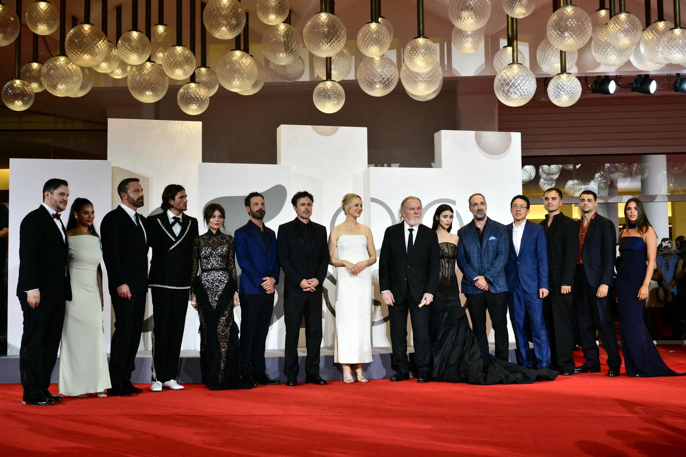 Assembled across a sweeping red carpet under a canopy of globe lights, the cast and crew of "Company" pose in a wide ensemble shot at the 83rd Venice International Film Festival at Venice Lido on September 8, 2026. | Source: Getty Images