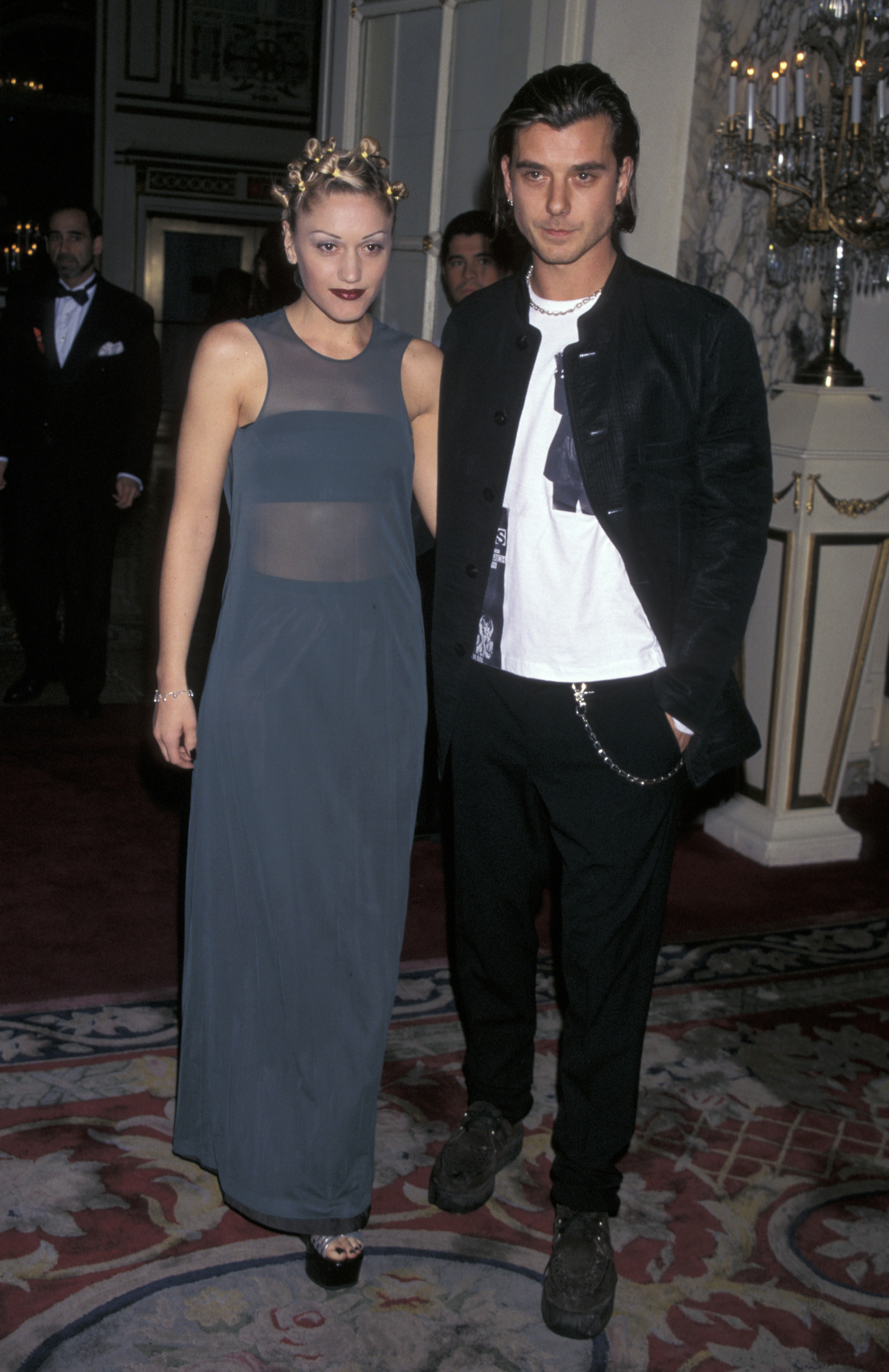 Gwen Stefani and Gavin Rossdale pose together at the 40th Annual Grammy Awards in 1998, with Stefani in a sheer blue gown and Rossdale in black-and-white layers.