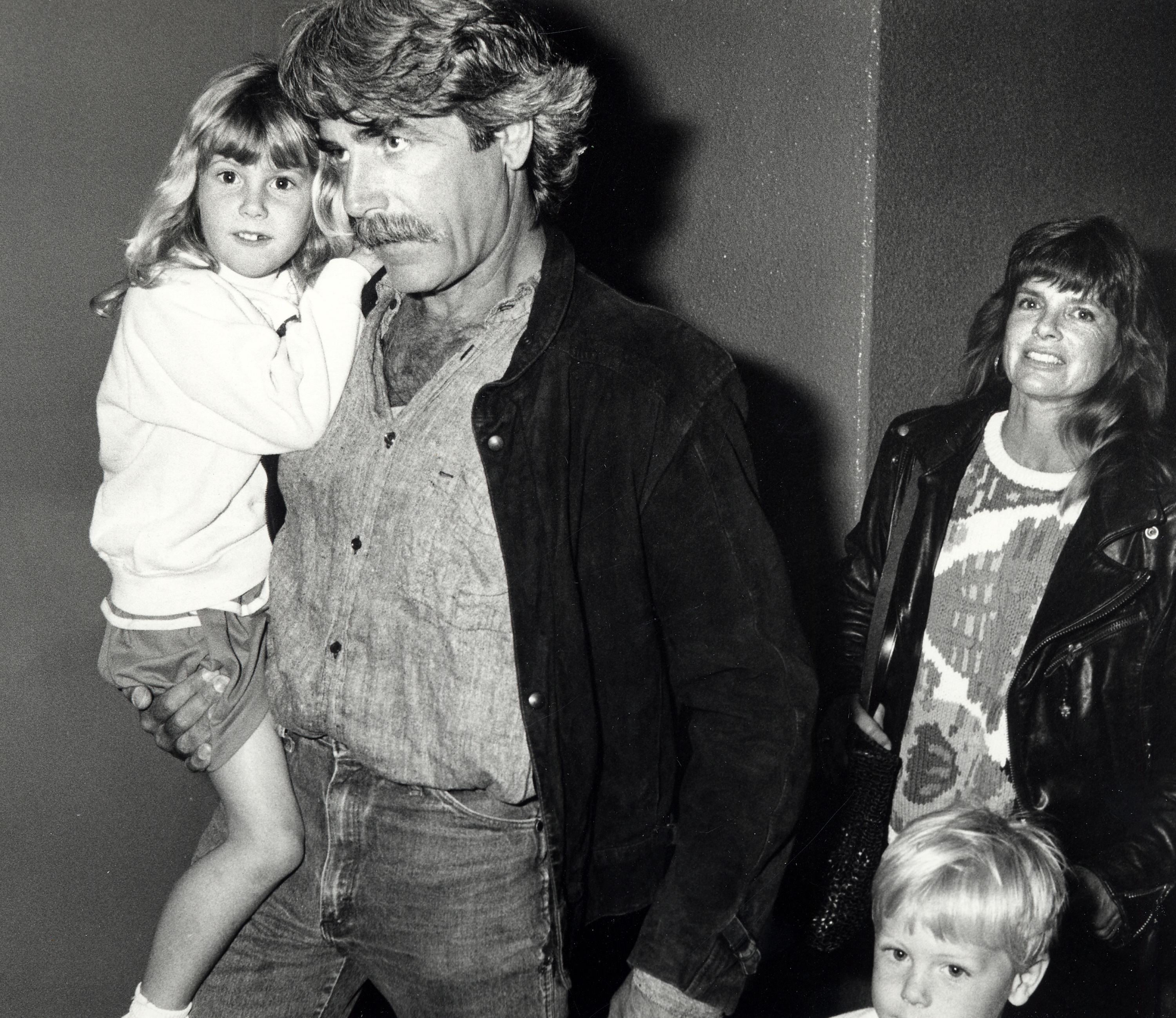 The distinguished actor carried his young daughter in his arms as the Hollywood couple enjoyed a family night out attending "The Moscow Circus" at the Great Western Forum on March 14, 1990, in Inglewood, California. Sporting his signature mustache and rugged dark jacket over jeans, the performer looked every bit the doting father alongside his glamorous actress wife, who followed closely behind in a leather jacket and patterned sweater, while their blonde little girl curiously observed the flashing cameras.