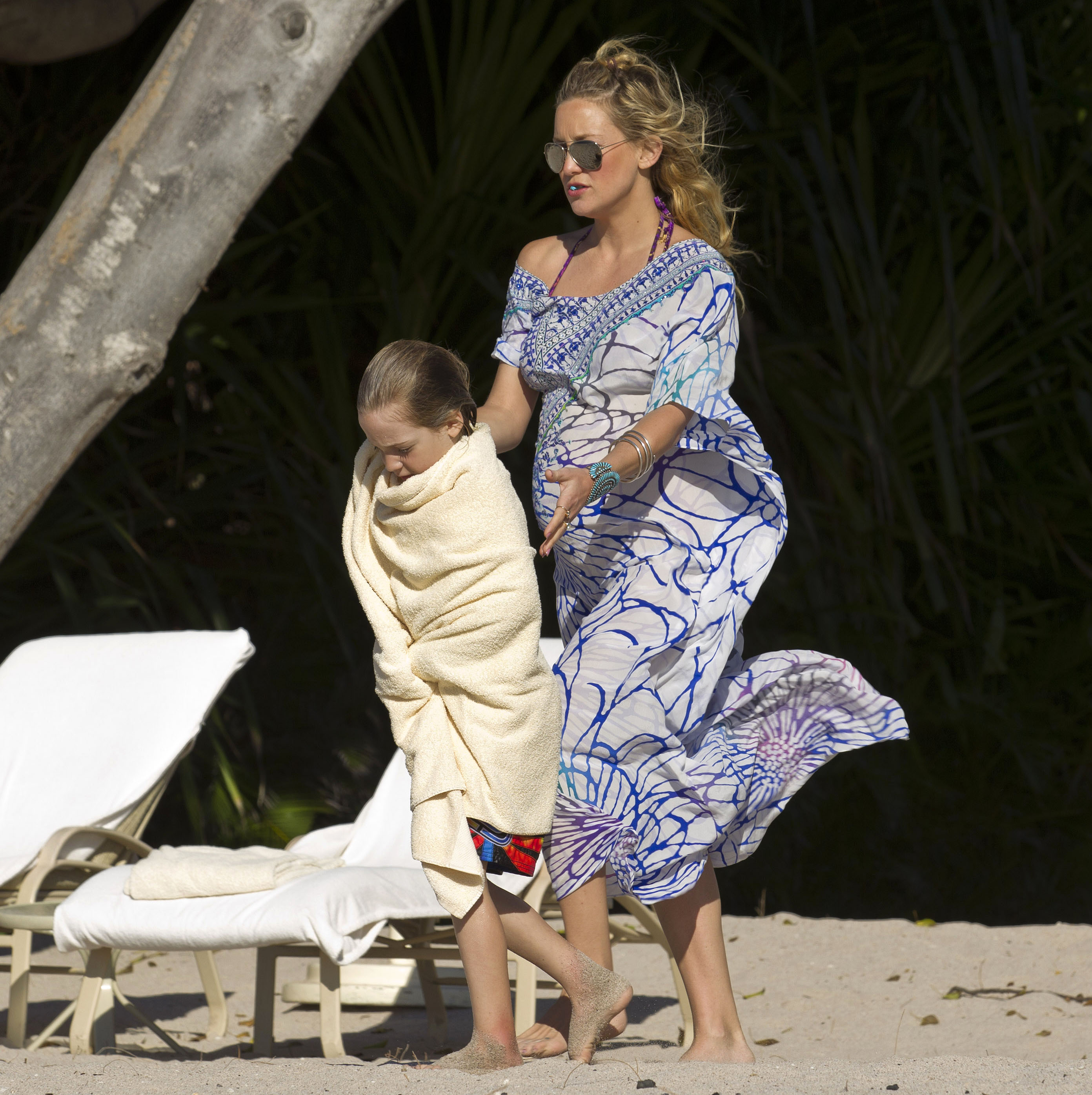 Kate Hudson was spotted walking barefoot on the sand, lovingly guiding her towel-wrapped son, Ryder Robinson. Wearing a flowing, off-the-shoulder, purple and blue printed cover-up and sunglasses, she exudeed laid-back elegance while tending to her child with warmth.
