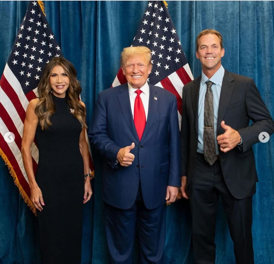 Kristi and Bryon Noem pose alongside Donald Trump, all smiling and giving thumbs-up gestures in front of U.S. flags. | Source: Instagram/kristinoem