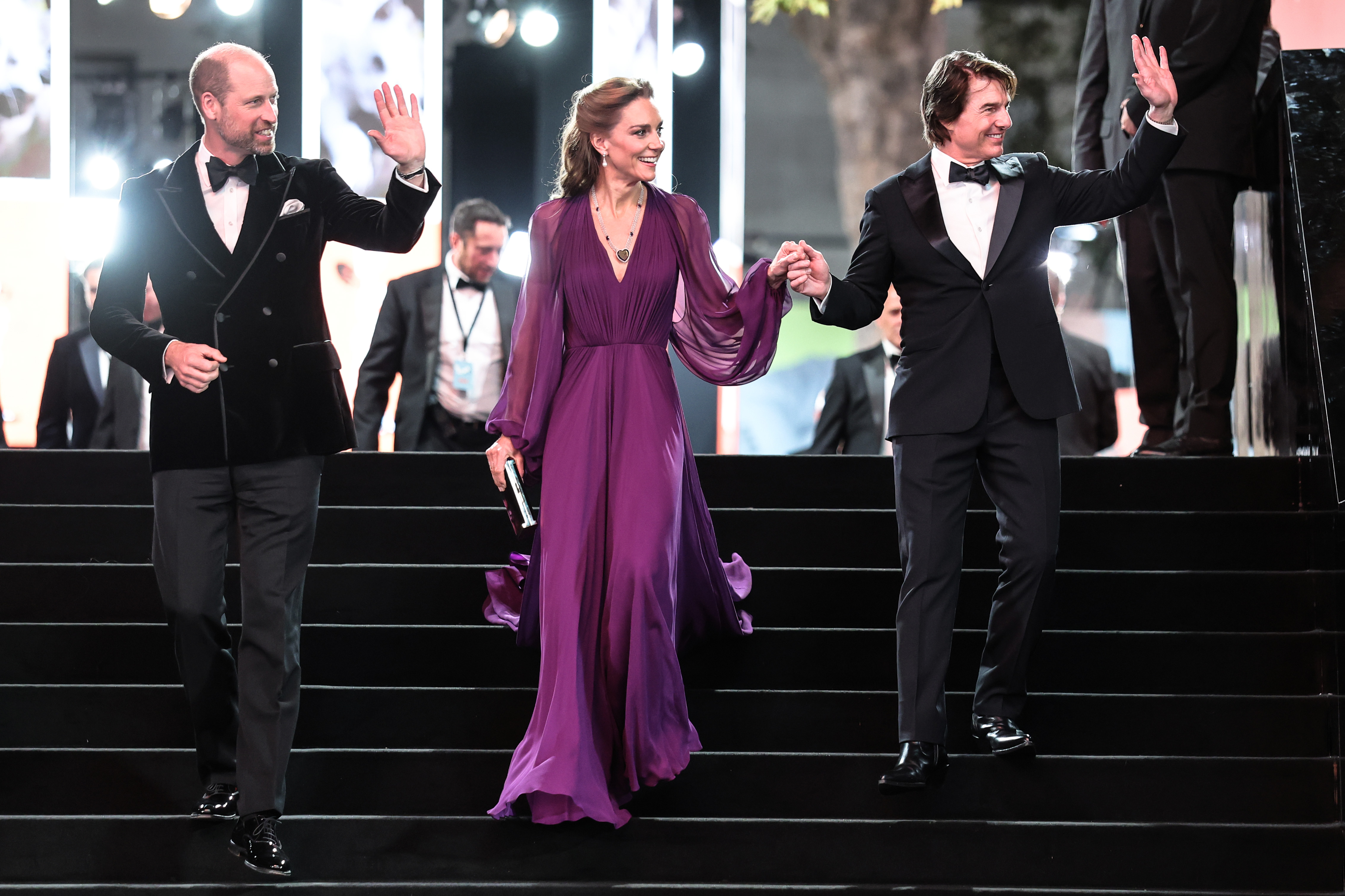 William, Catherine and Tom are photographed together on the steps during the "Digger" World Premiere and Royal Film Performance. Catherine holds Tom's hand while William and Tom raise their other hands.