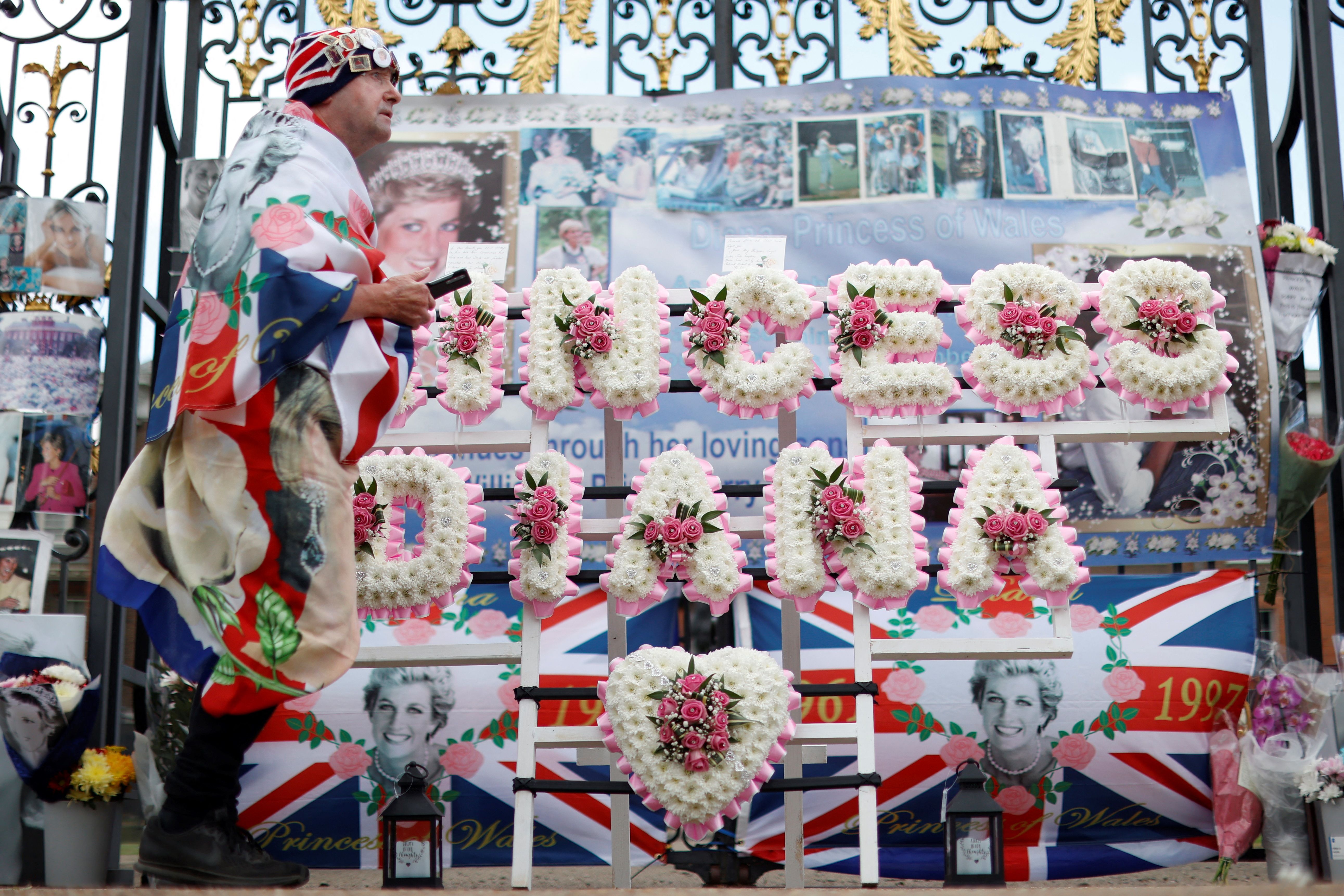 A man wrapped in the British national flag in front of a memorial for Diana, Princess of Wales, in front of Kensington Palace in London, England, on August 31, 2022. | Source: Getty Images