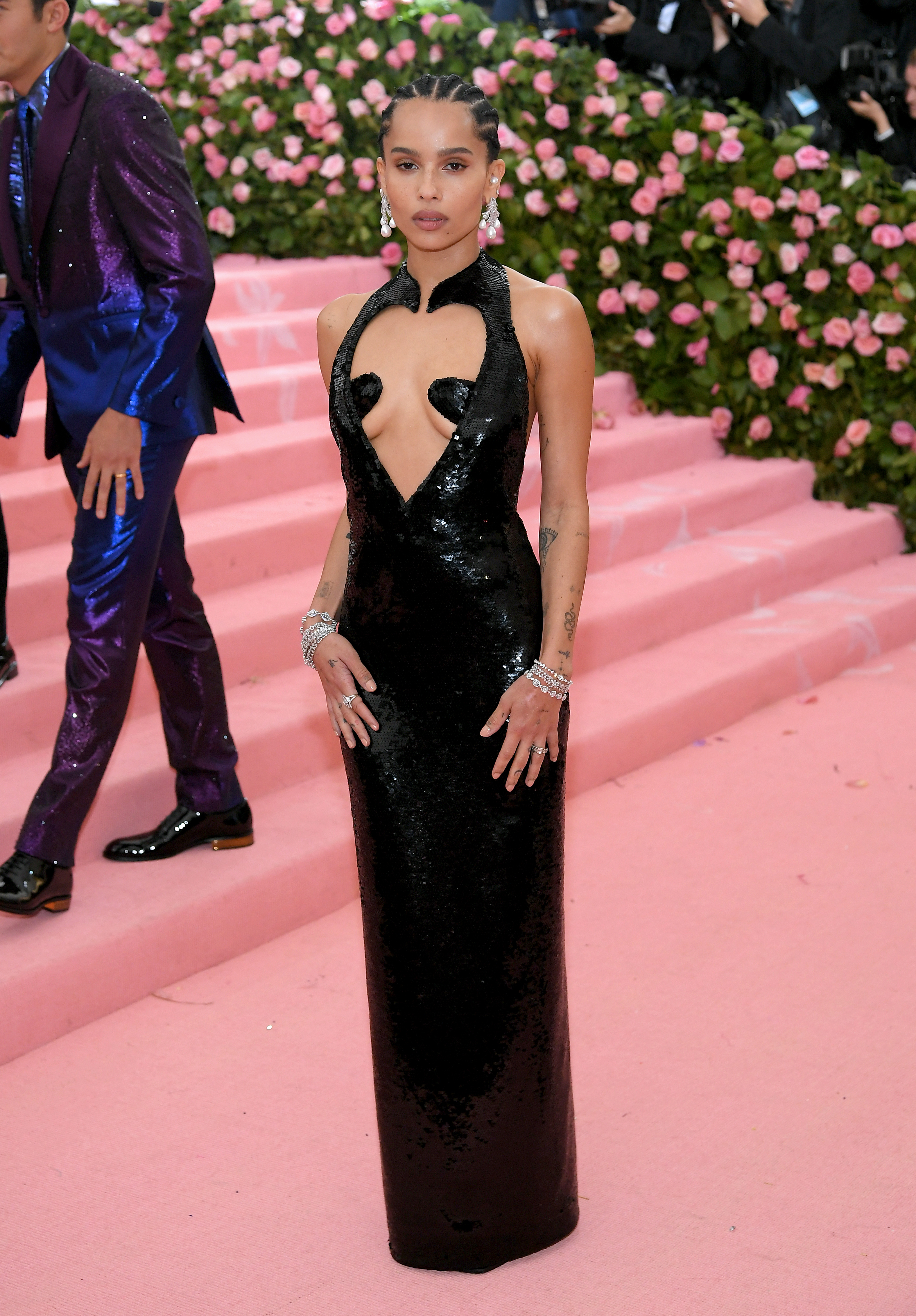 Zoë Kravitz attended the "Met Gala: Camp – Notes on Fashion" at the Metropolitan Museum of Art in New York City on May 6. She wore a black sequin halter gown with bold cutouts and a sculpted neckline, accessorized with dangling earrings, stacked diamond bracelets, and sleek cornrows.