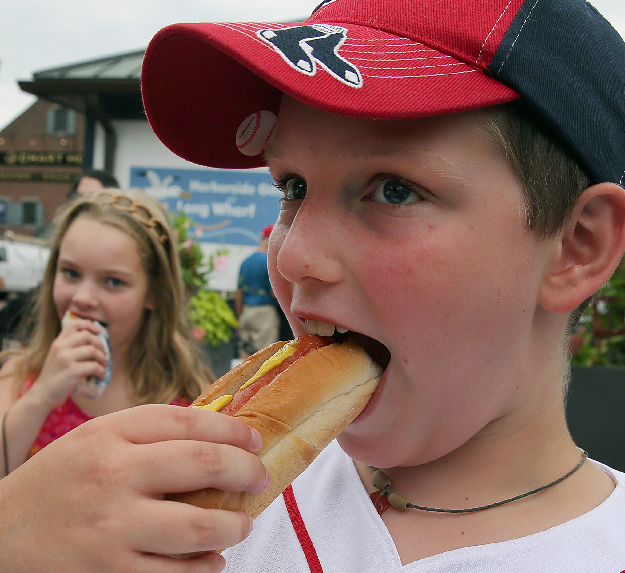 A young baseball fan eats a hot dog topped with mustard, a classic ballpark staple closely associated with Kayem's Fenway Frank. | Source: Getty Images